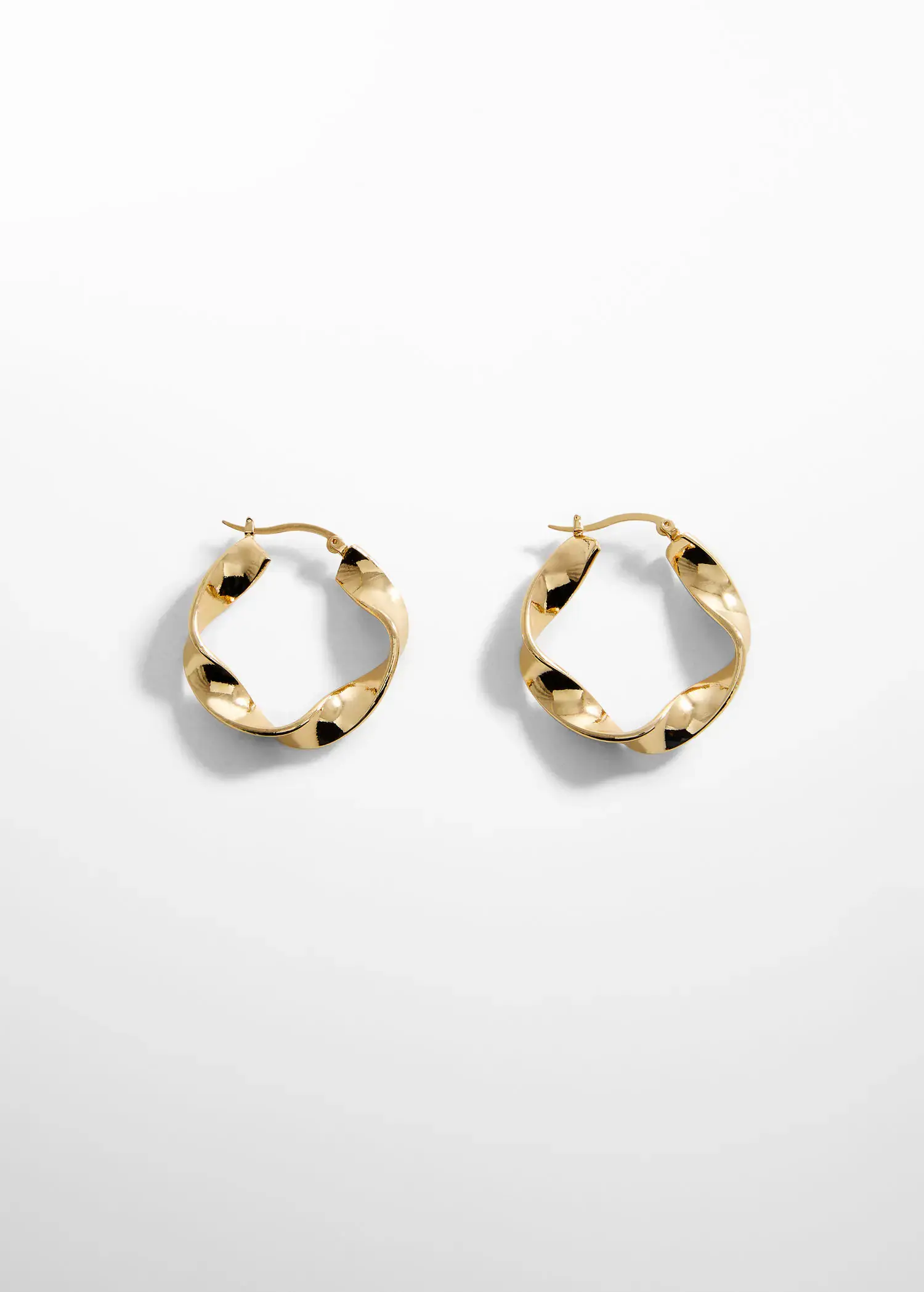 Mango Twisted hoop earrings. a pair of gold earrings on top of a table. 