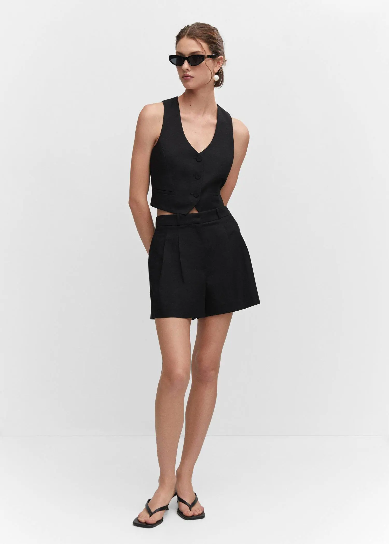 Mango Pleated high-waist shorts. a woman in a black dress posing for a picture. 