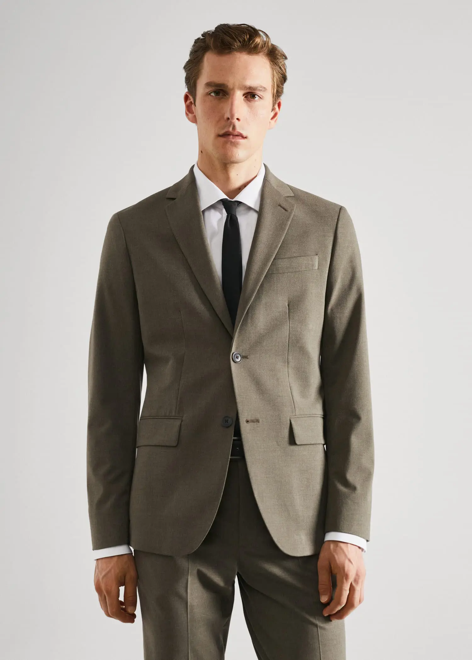 Mango Stretch fabric slim-fit suit blazer. a man wearing a suit and tie standing in front of a white wall. 