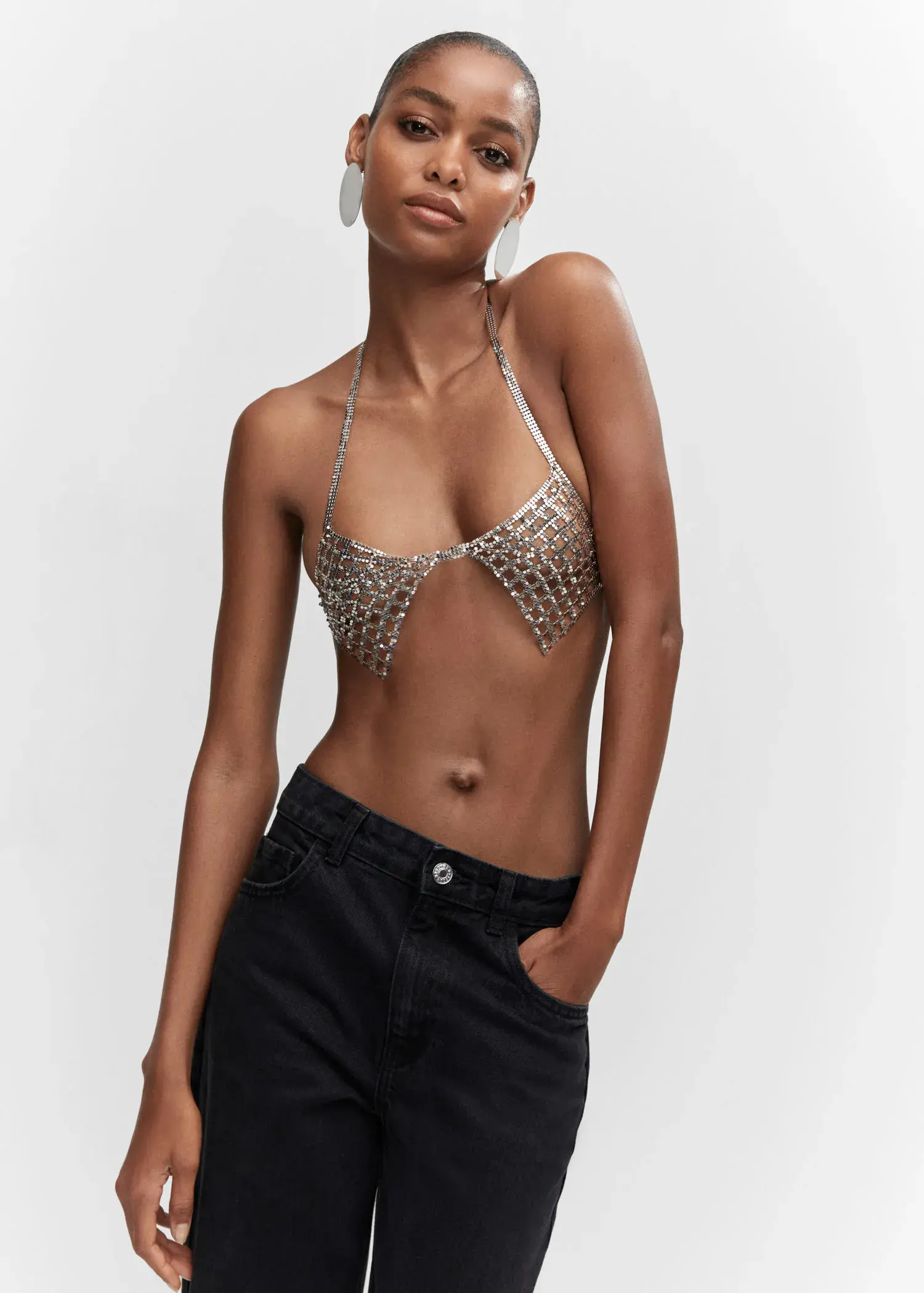 Mango Metallic mesh bra. a woman in a silver bikini top and black shorts. 
