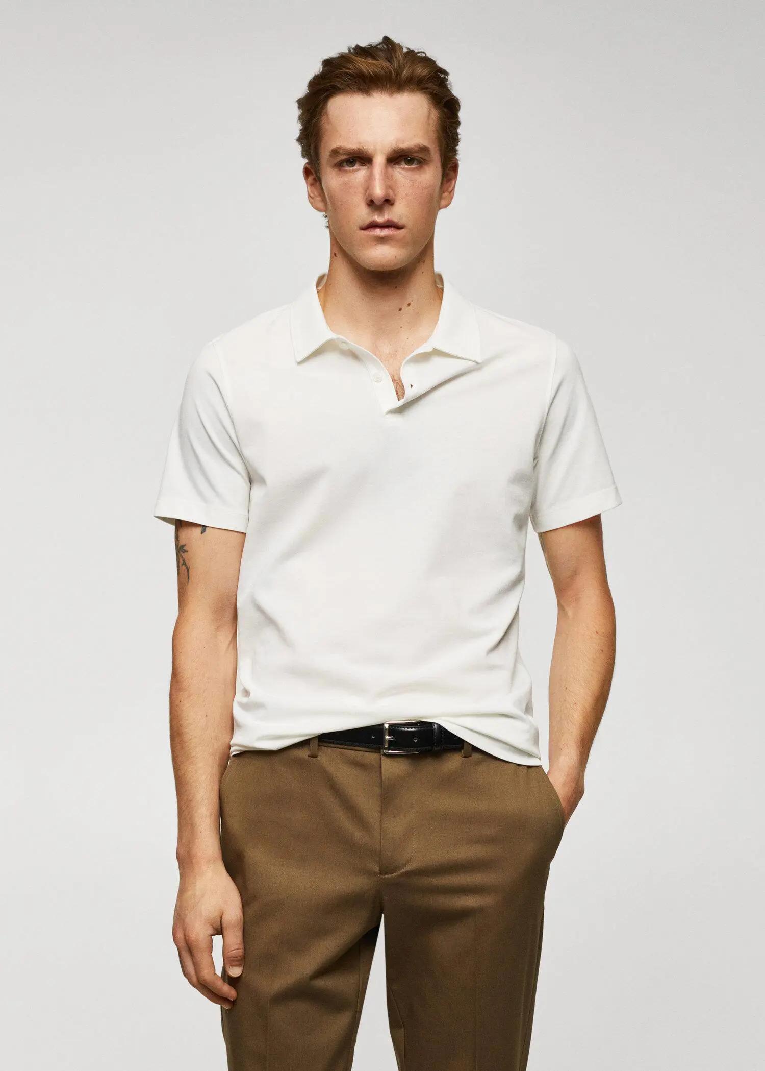 Mango Slim-fit textured cotton polo shirt. a man in a white shirt and brown pants. 