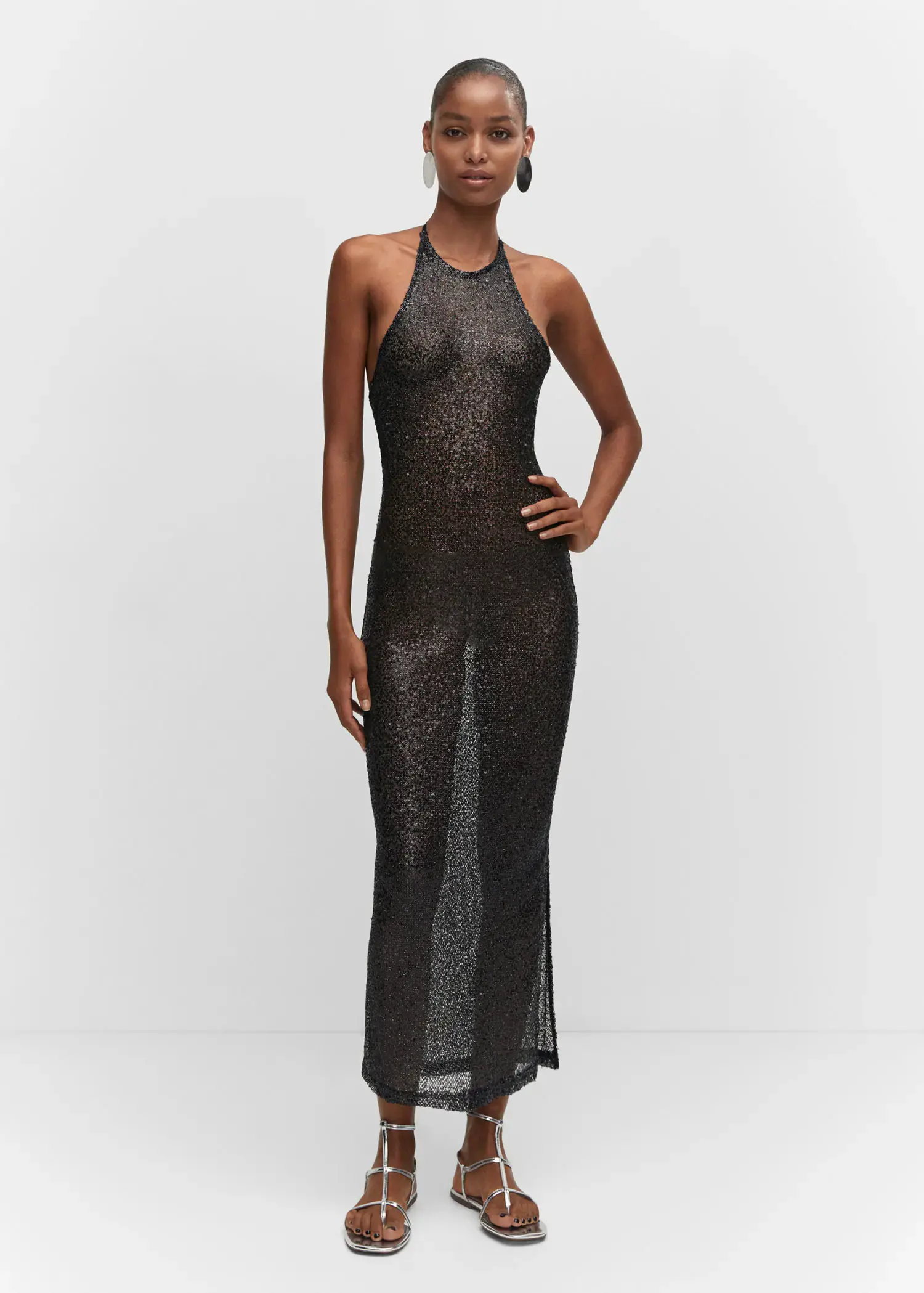 Mango Side slit sequined gown. a woman in a black dress standing in front of a white wall. 