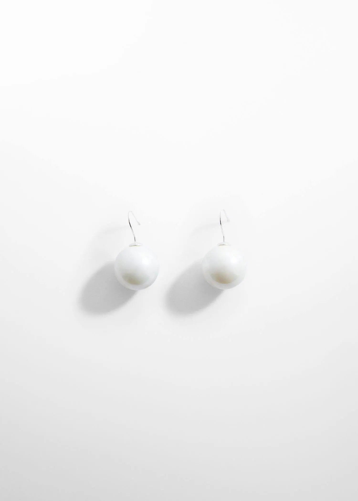 Mango Pearl crystal earrings. a pair of white earrings hanging on a white wall. 