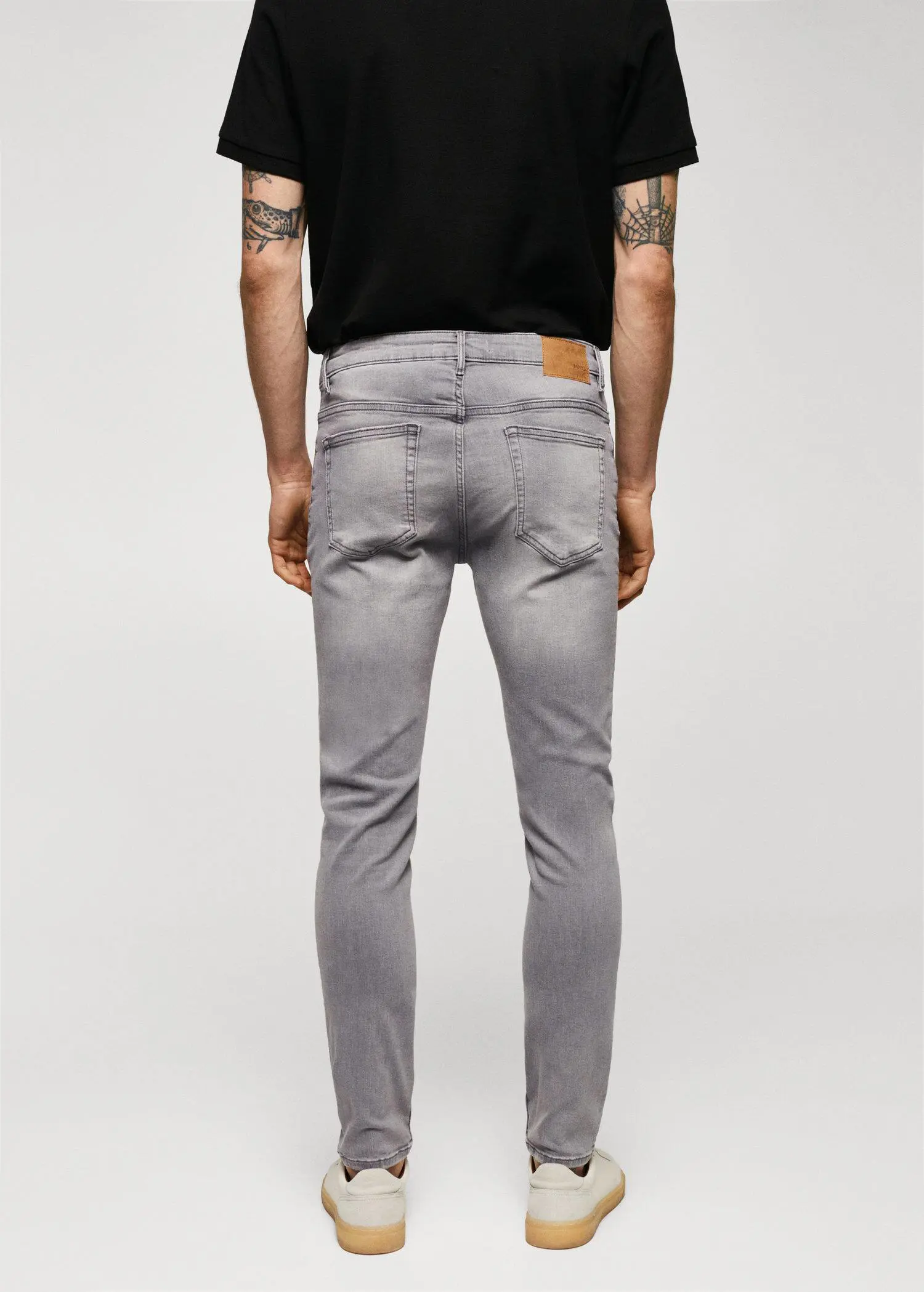 Mango Jude skinny-fit jeans. a person wearing grey jeans and a black shirt. 