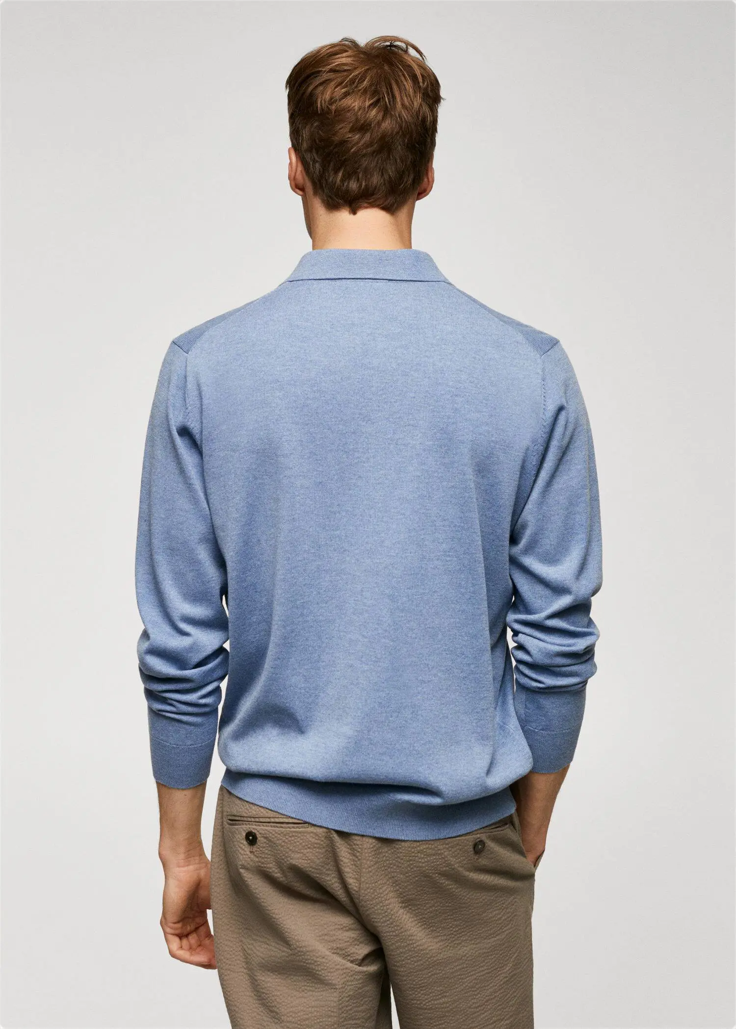 Mango Long-sleeved cotton jersey polo shirt. a man wearing a light blue sweater standing in front of a wall. 