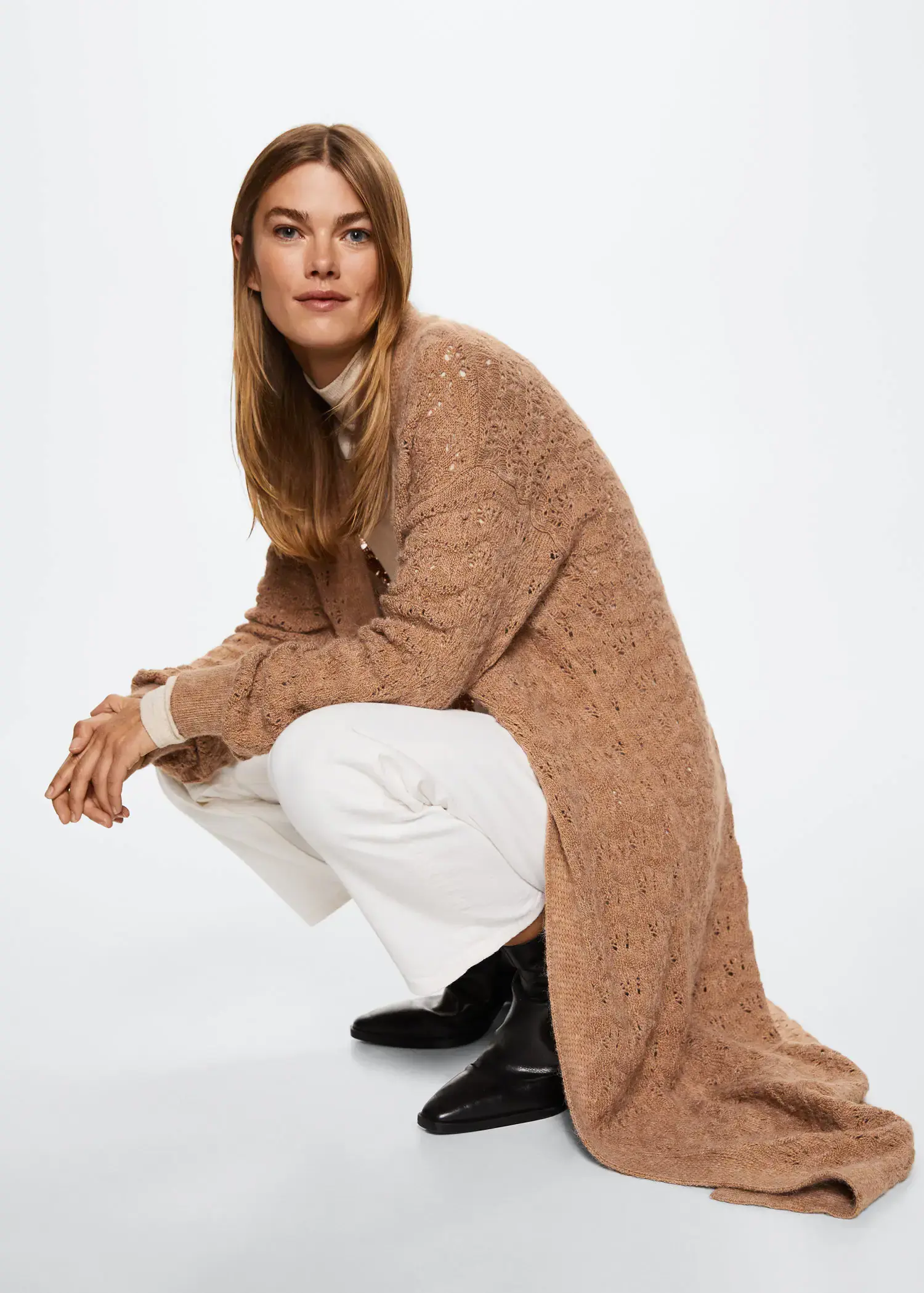 Mango Openwork long cardigan. a woman kneeling on the ground wearing a sweater. 