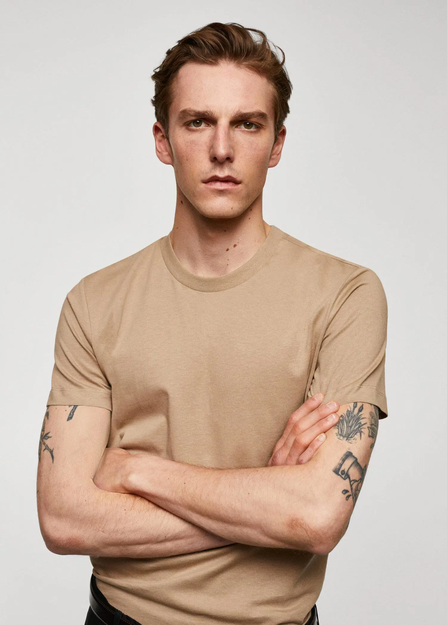 Mango Basic cotton stretch T-shirt. a young man with his arms crossed wearing a tan shirt. 