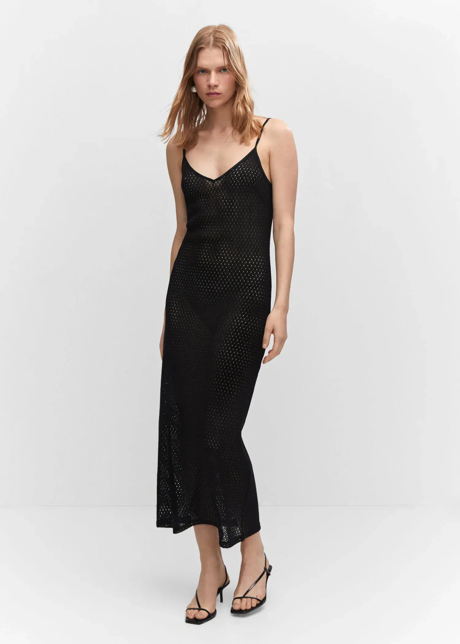 Mango Long openwork knitted dress. a woman in a black dress standing in front of a white wall. 