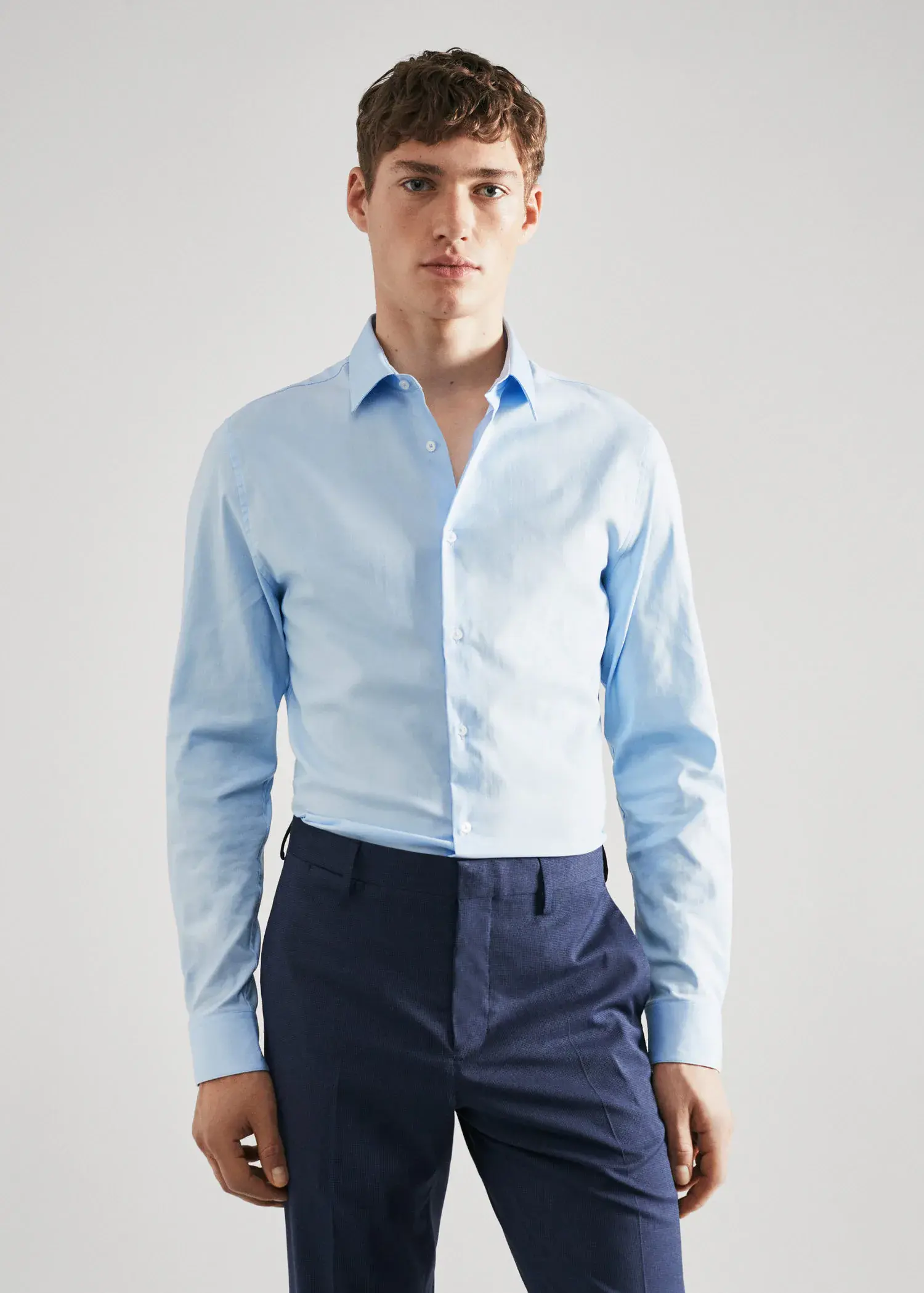 Mango Super slim-fit poplin suit shirt. a man wearing a light blue shirt and blue pants. 