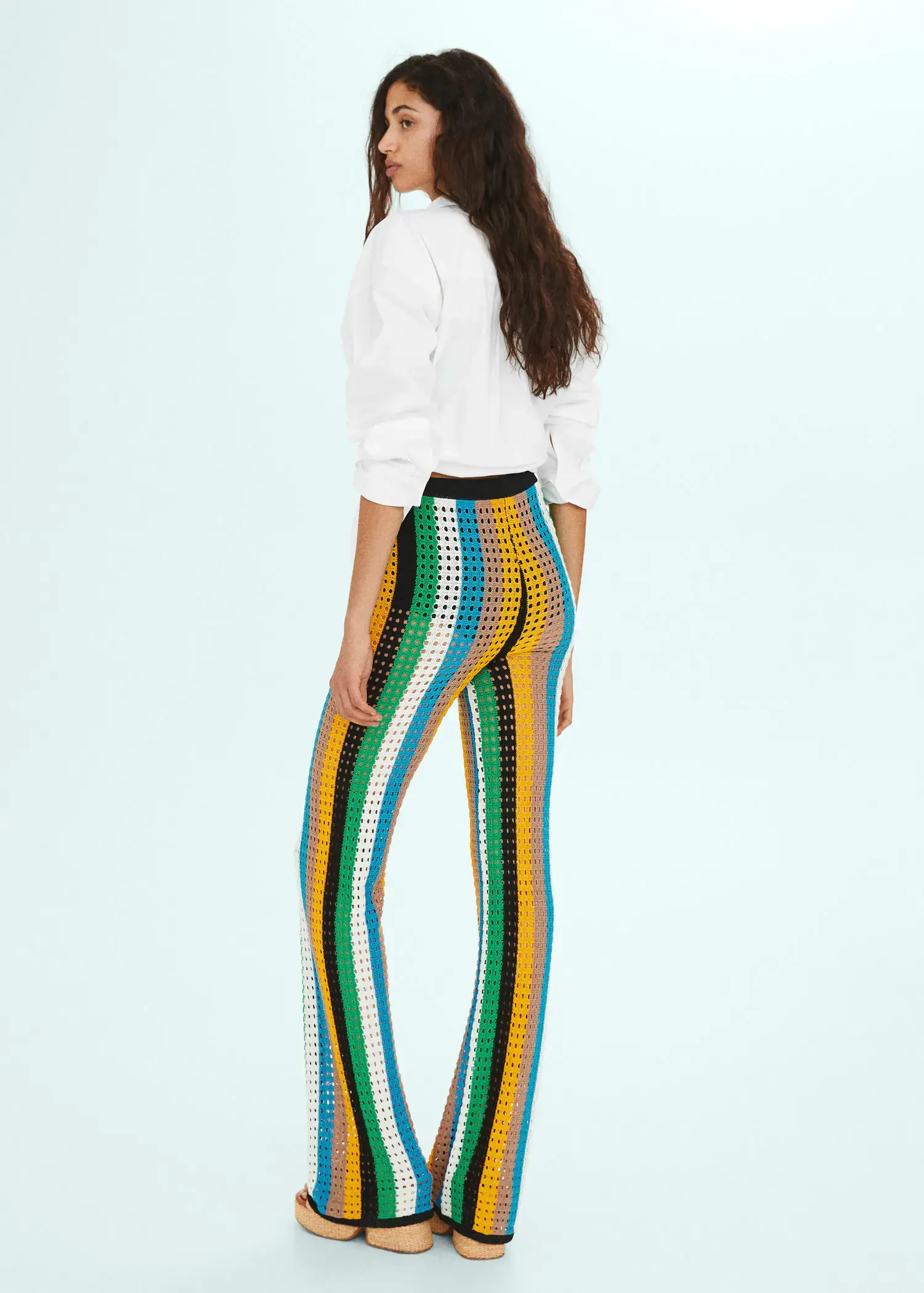 Mango Openwork knit trousers. a woman wearing a white shirt and colorful pants. 