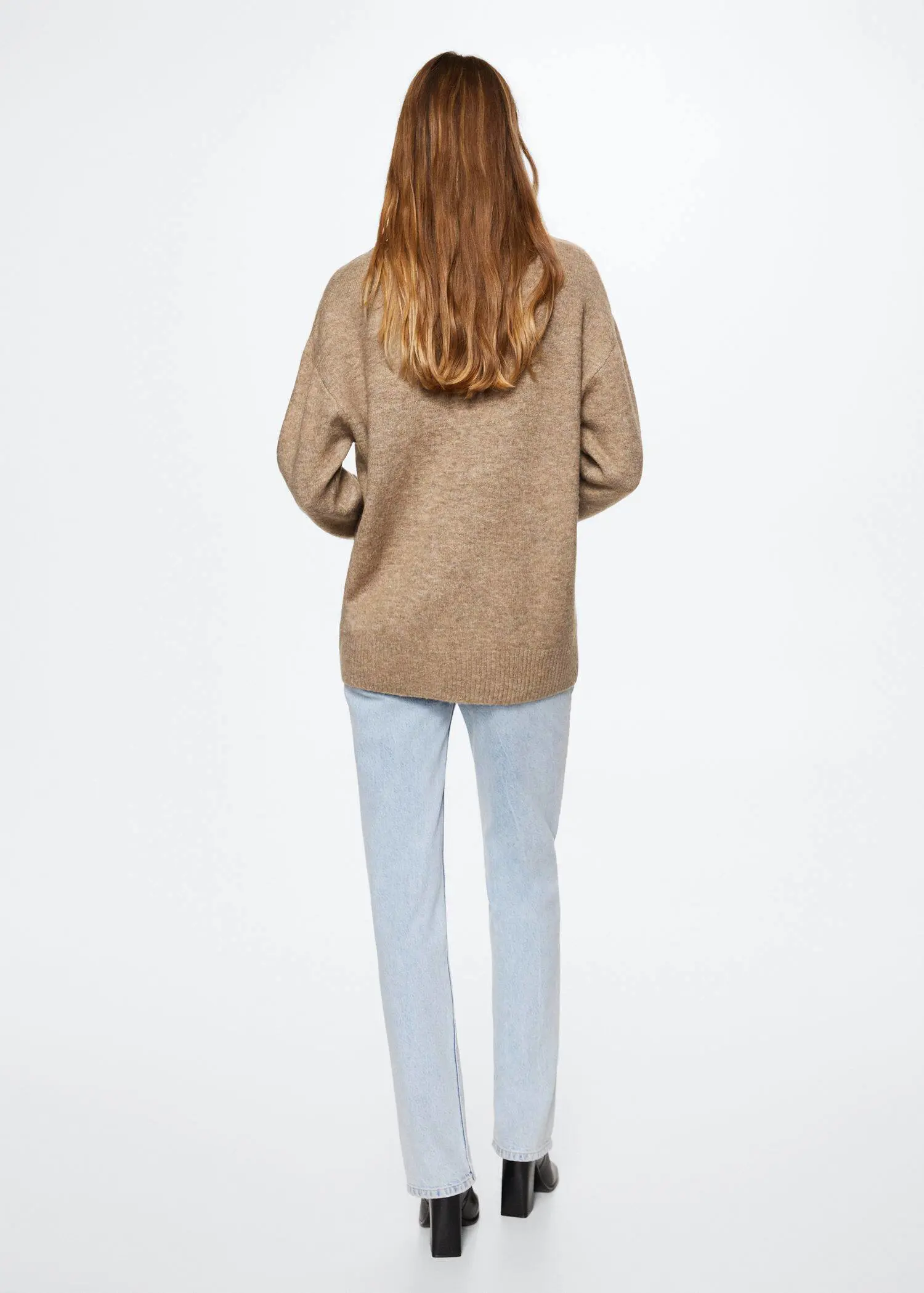 Mango V-neck sweater. a woman standing in front of a white wall. 