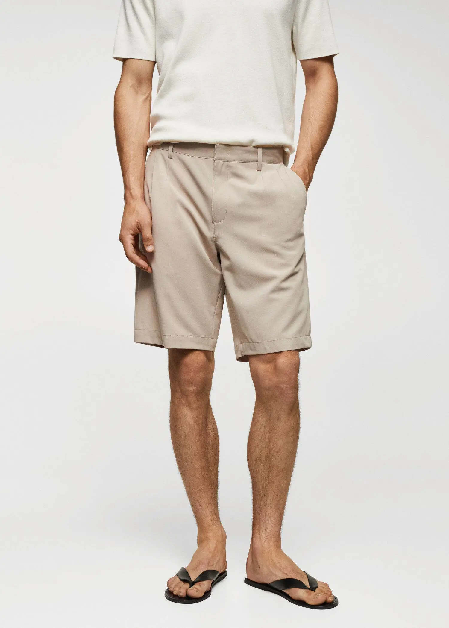Mango Cotton pleated Bermuda shorts. a man wearing a pair of beige shorts. 