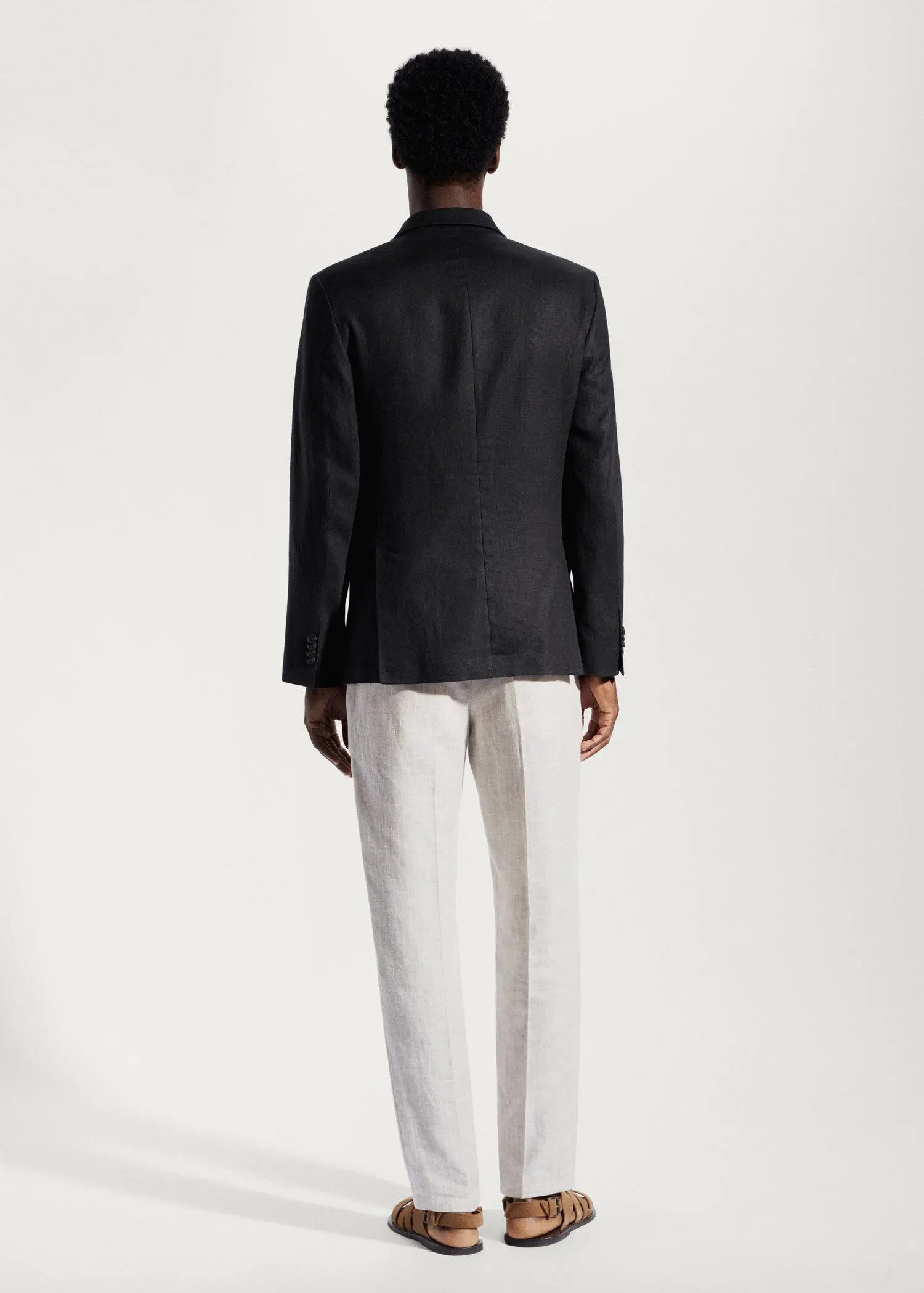 Mango 100% linen slim fit blazer. a man wearing a black jacket and white pants. 