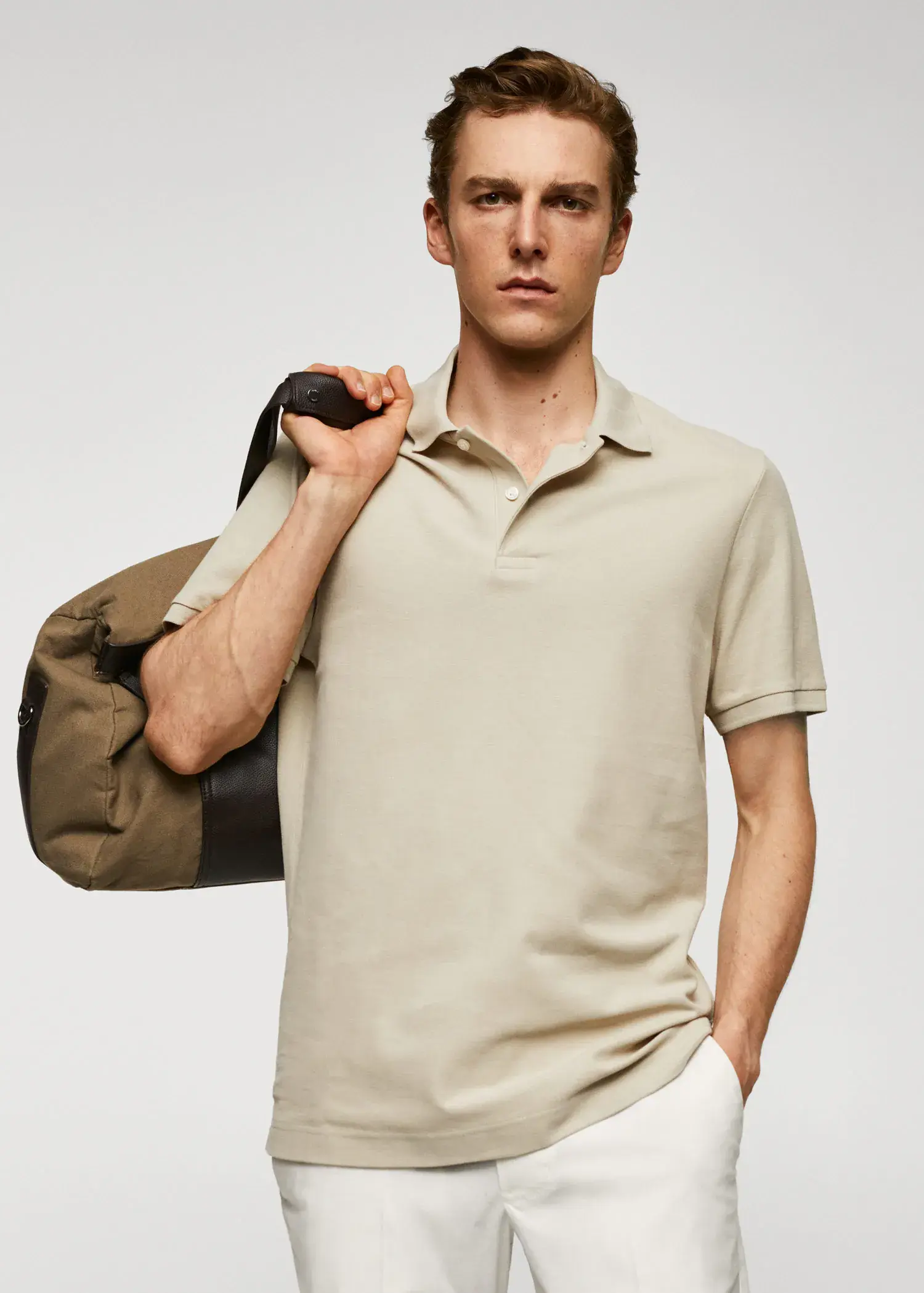 Mango 100% cotton pique polo shirt. a man in a beige polo shirt holding a brown bag. 