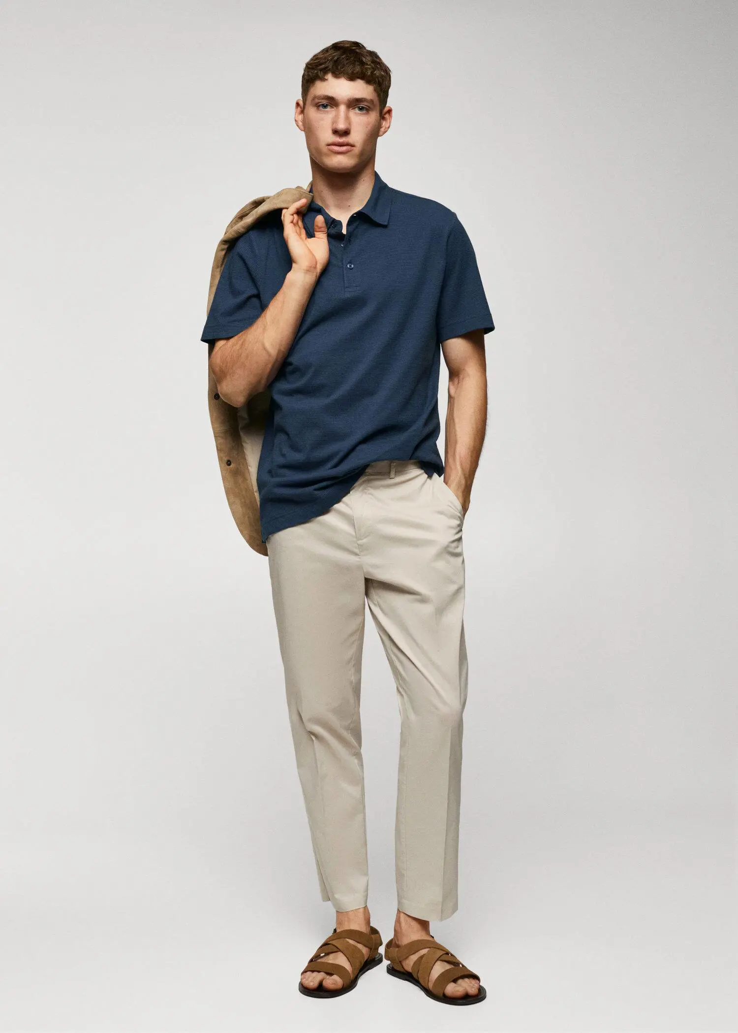 Mango 100% cotton polo shirt with striped structure. a man in a blue polo shirt and beige pants. 