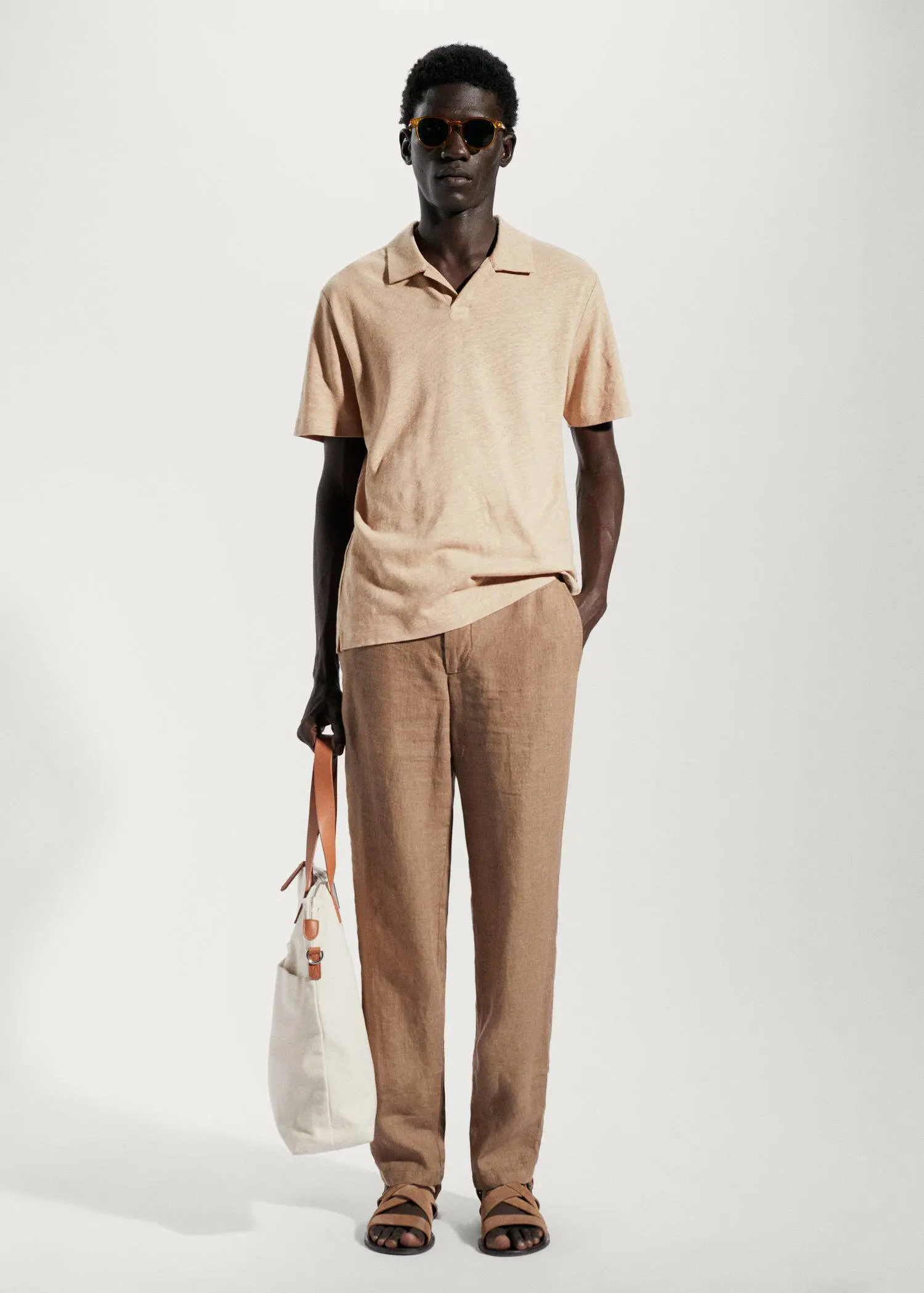 Mango Cotton linen slim-fit polo shirt. a man in a tan shirt and tan pants holding a white bag. 