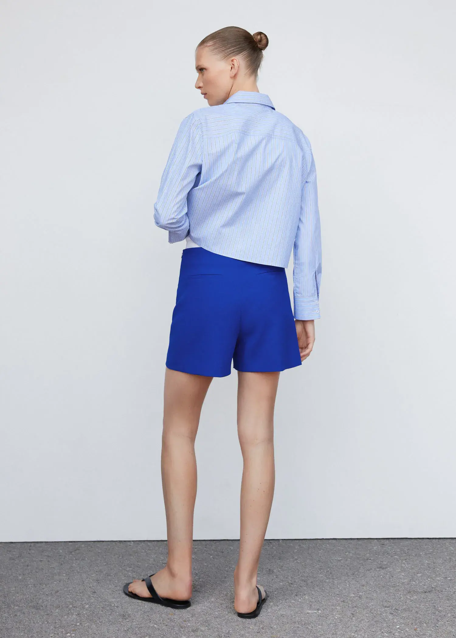 Mango High-waist straight shorts. a person standing in front of a white wall. 