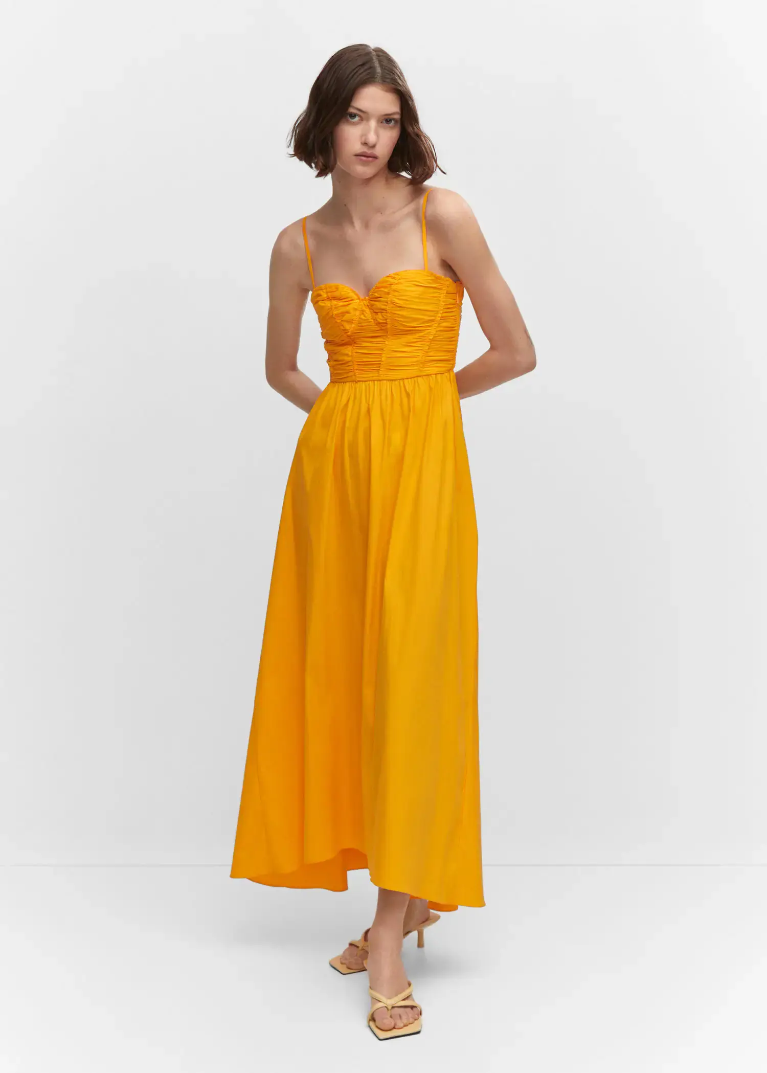 Mango Flared corset dress. a woman in a yellow dress standing in front of a white wall. 