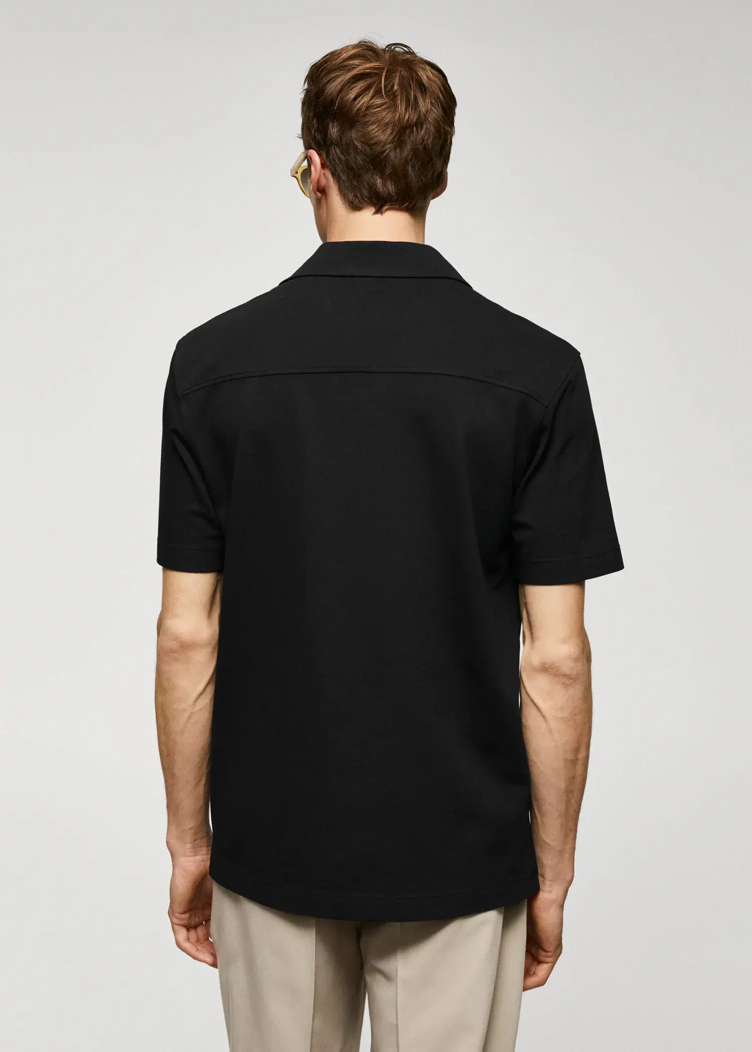 Mango Bowling-collar pique shirt. a man in a black shirt is standing in front of a white wall. 