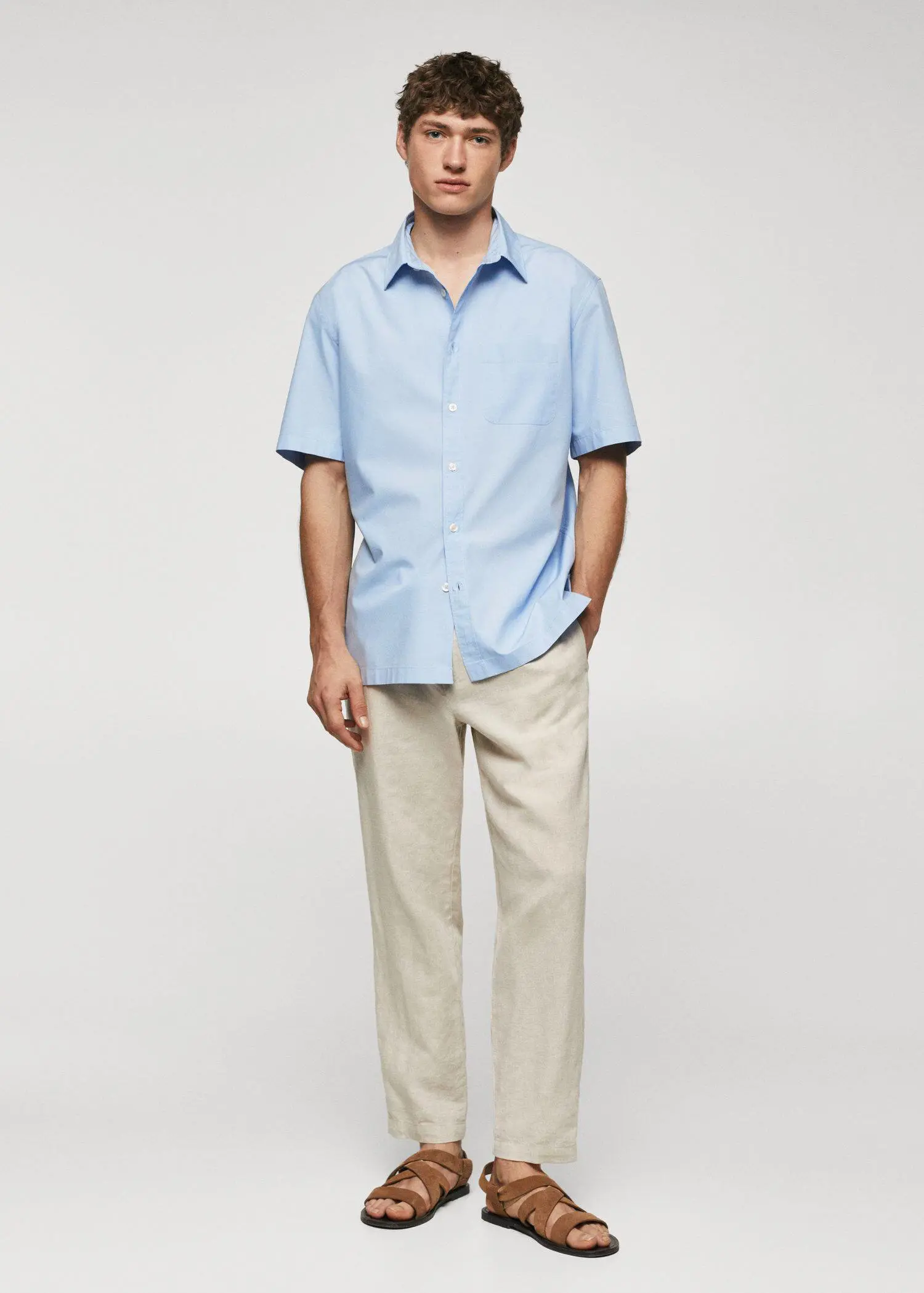 Mango Regular-fit cotton short sleeve shirt. a man in a light blue shirt and beige pants. 