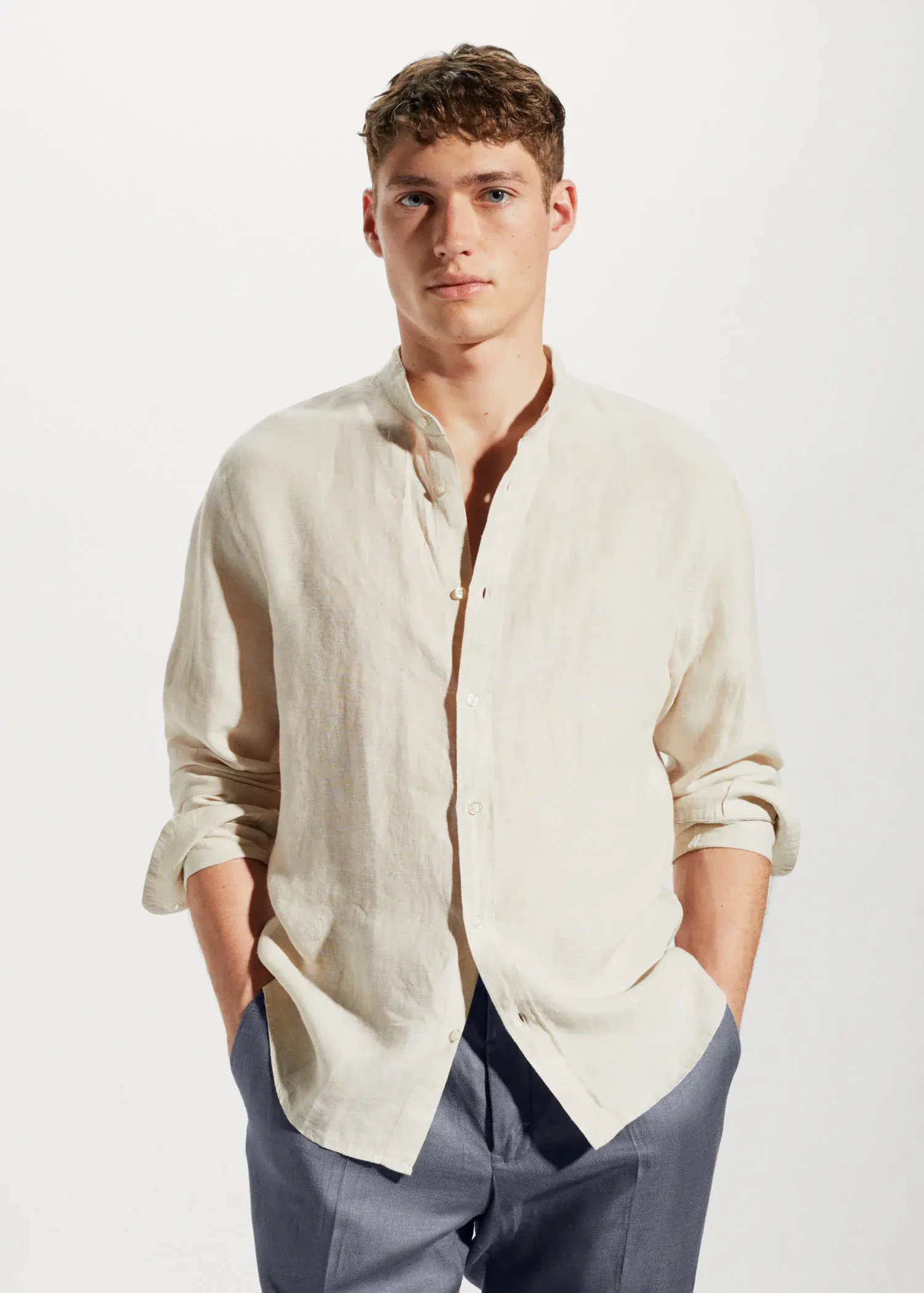Mango 100% linen Mao collar shirt. a man in a white shirt is standing with his hands in his pockets 
