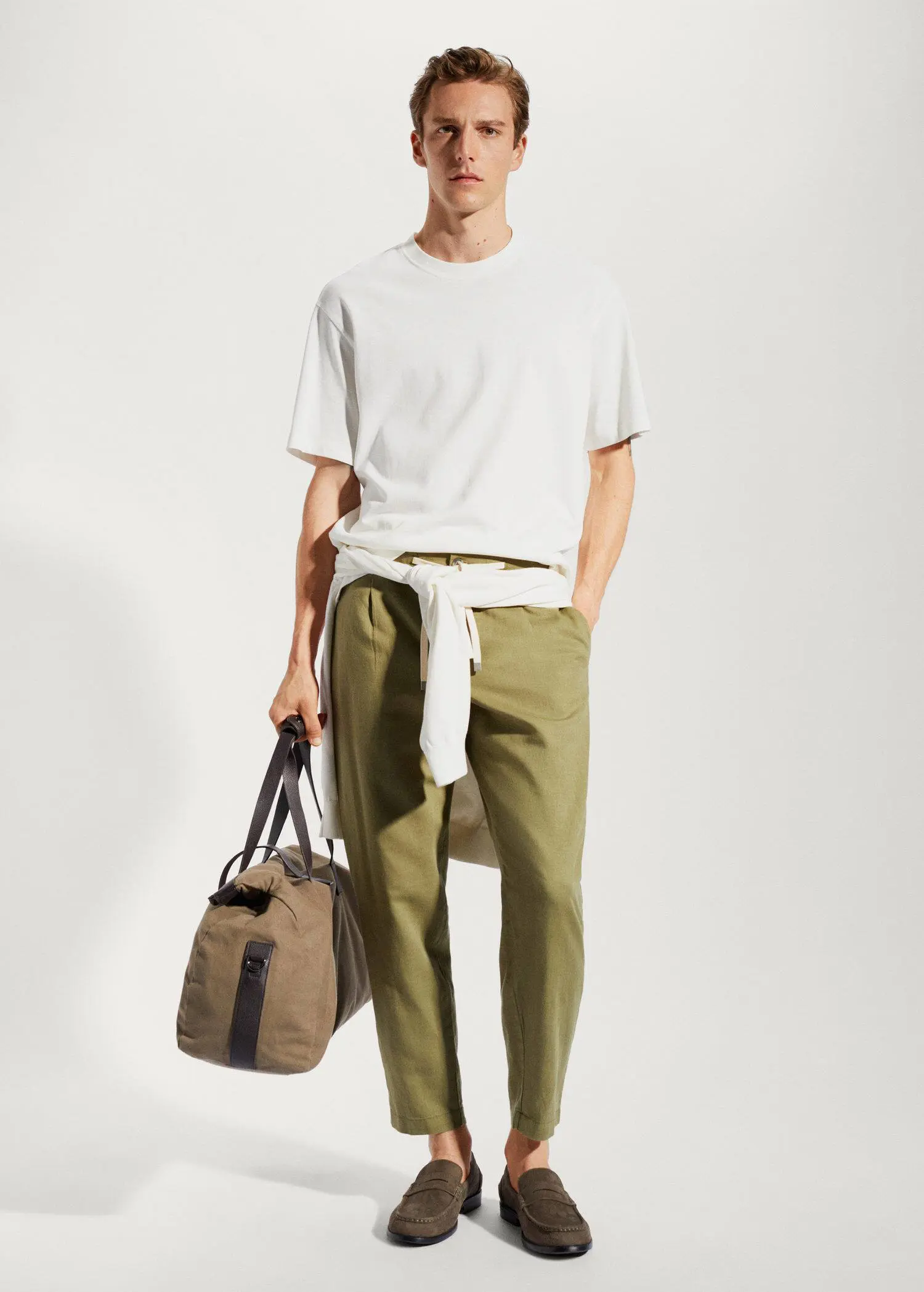 Mango Slim-fit pants with drawstring . a man holding a bag in front of a wall. 