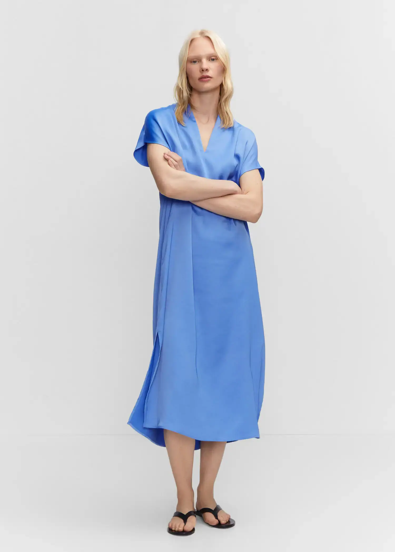 Mango Side slit dress. a woman in a blue dress standing with her arms crossed. 