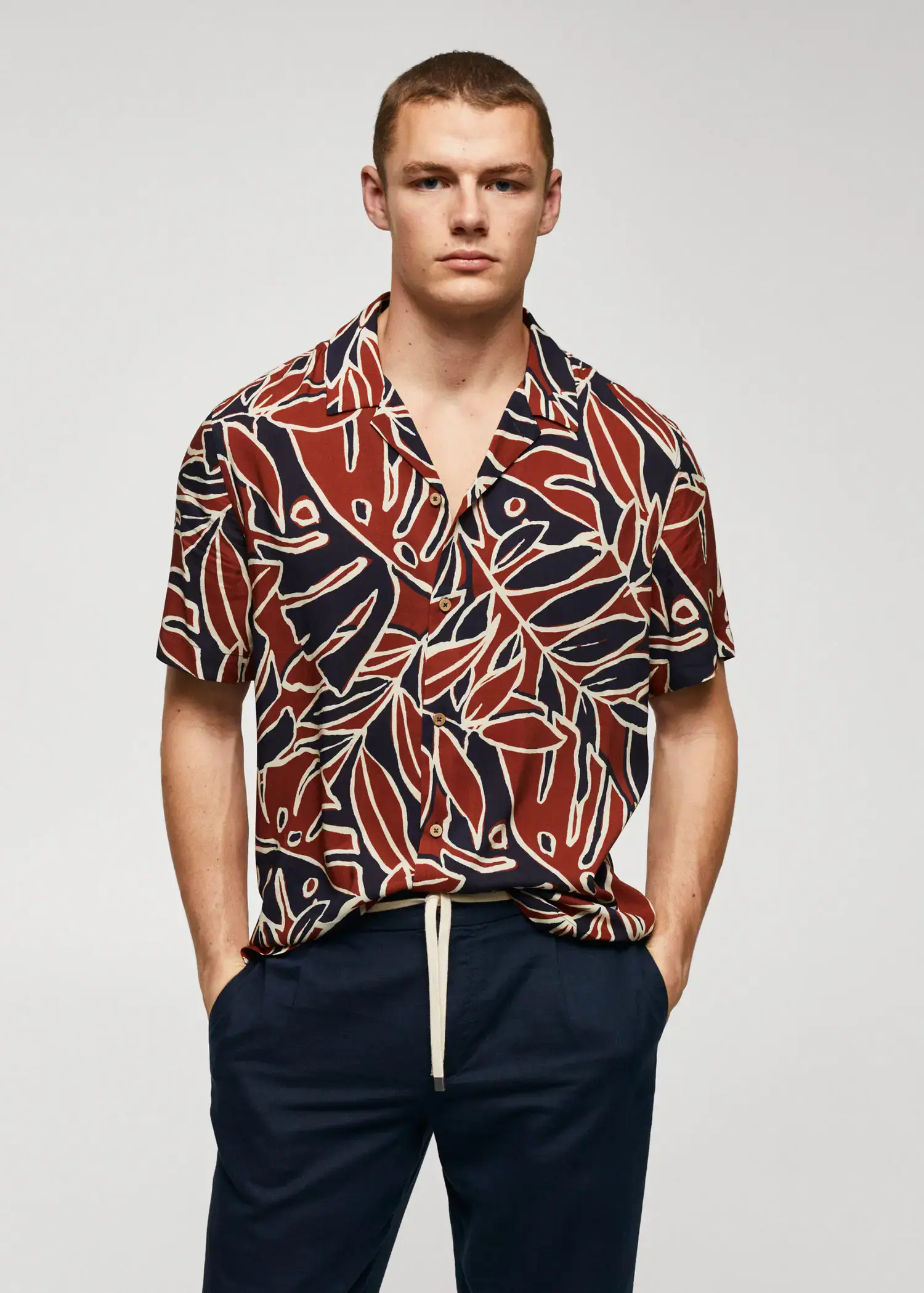 Mango Bowling shirt with leaf print. a man in a red and black shirt is holding his hands in his pockets. 