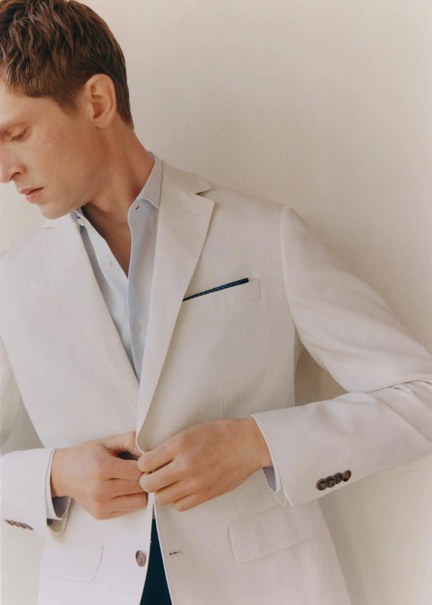 Mango 100% linen suit blazer. a man in a white suit is fixing his tie. 