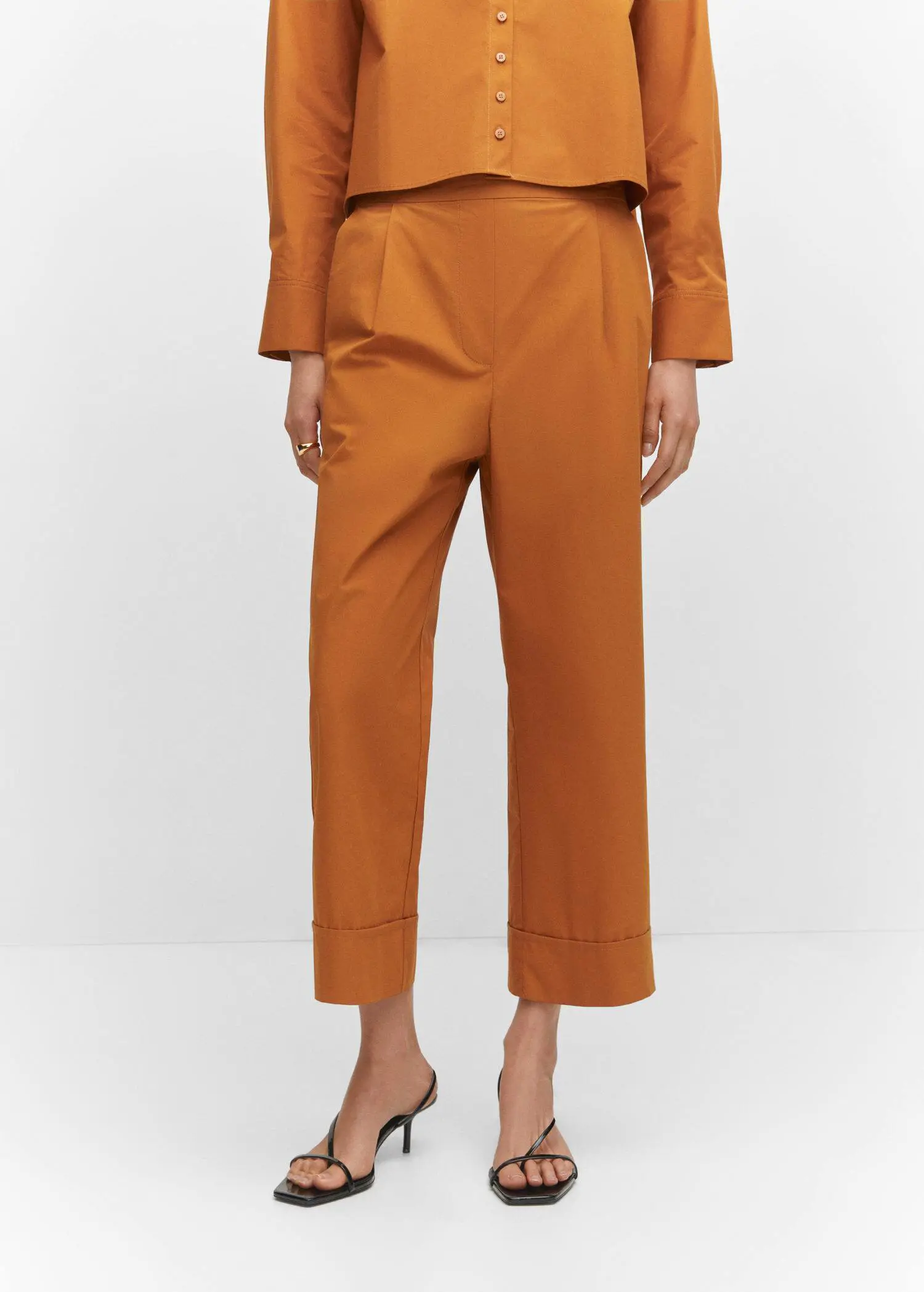 Mango Pleated culottes pants. a person standing in front of a white wall. 