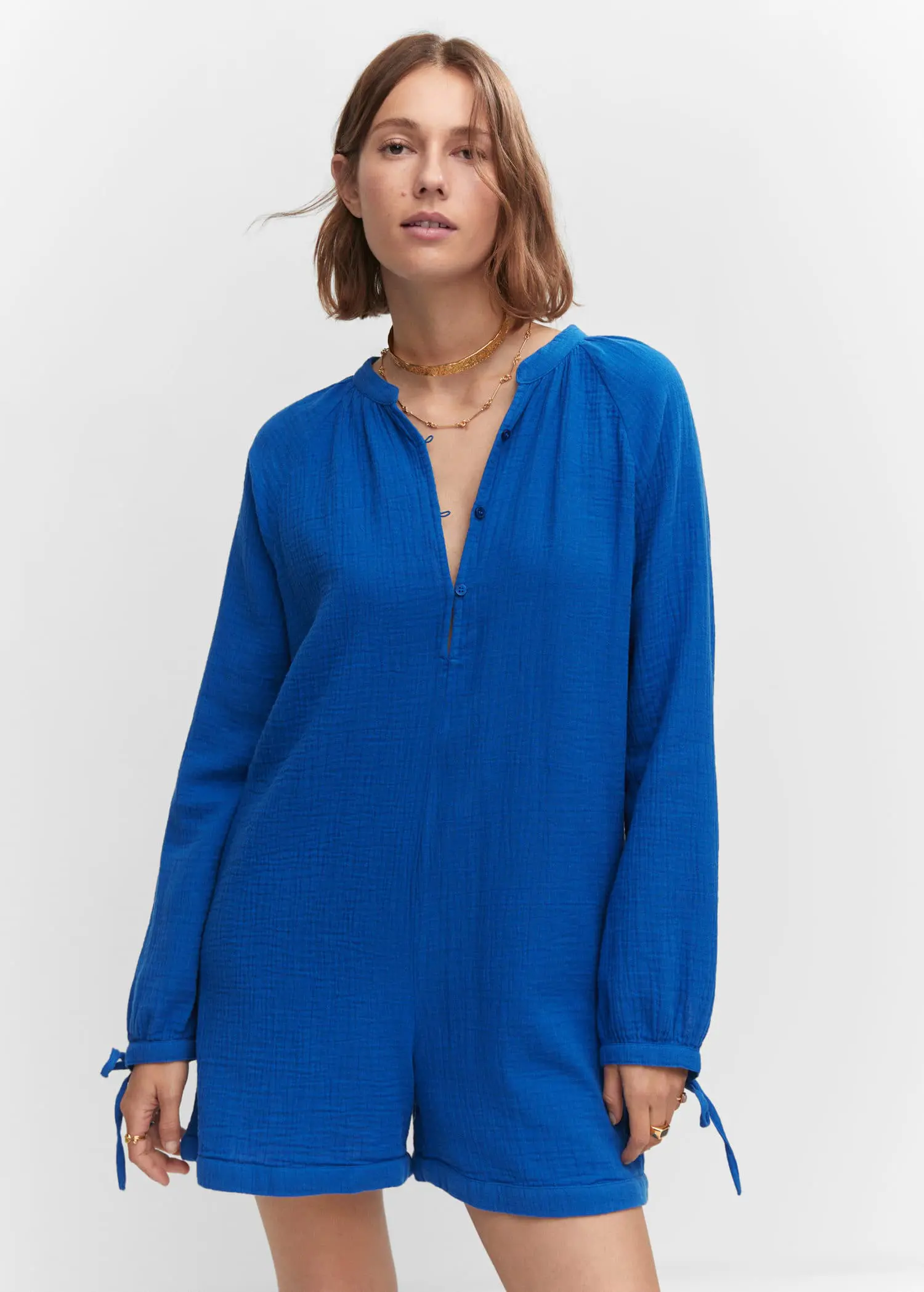 Mango Short jumpsuit with buttons. a woman wearing a blue jumpsuit and a gold necklace. 