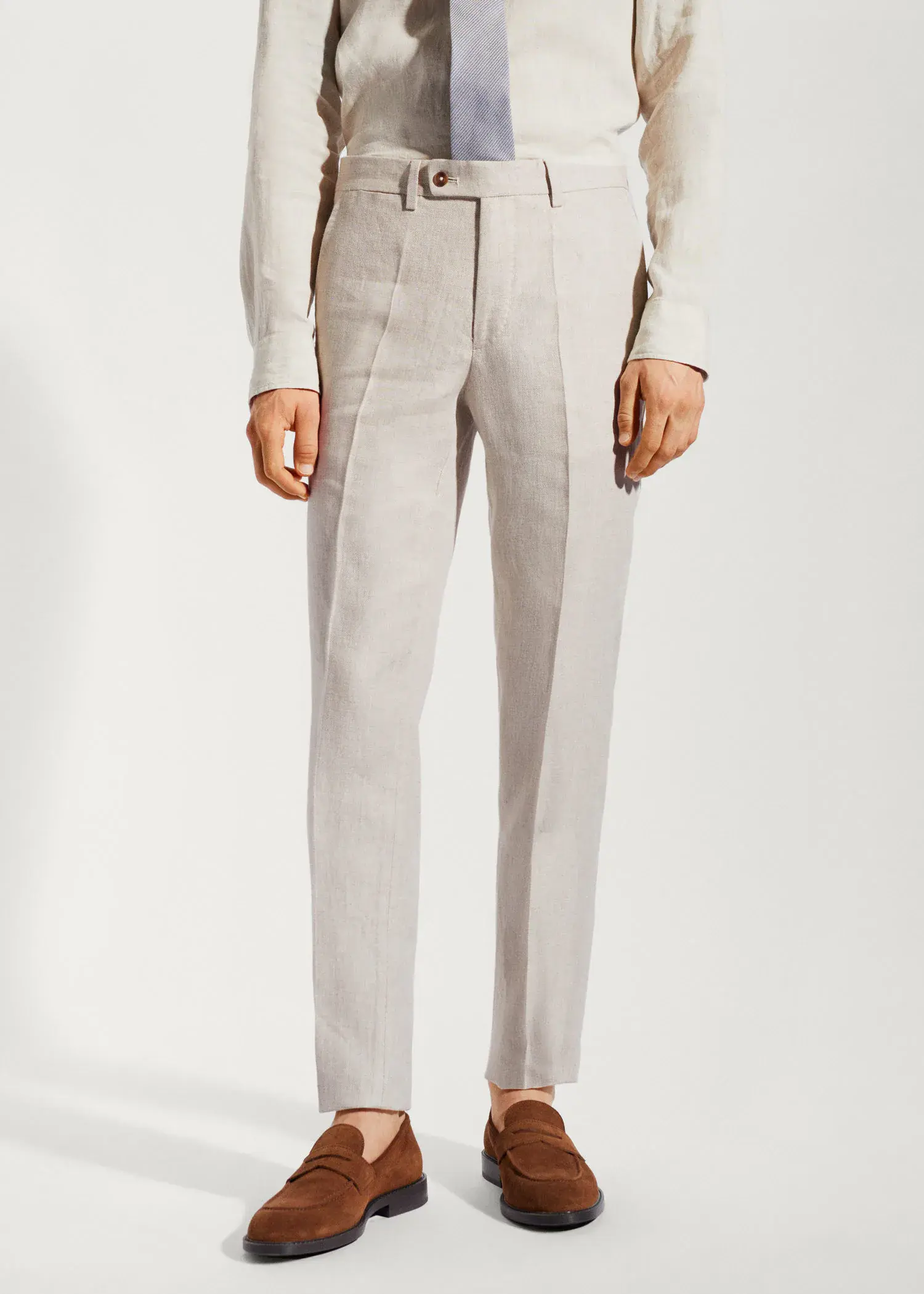 Mango 100% linen suit trousers. a man wearing a suit standing in front of a white wall. 