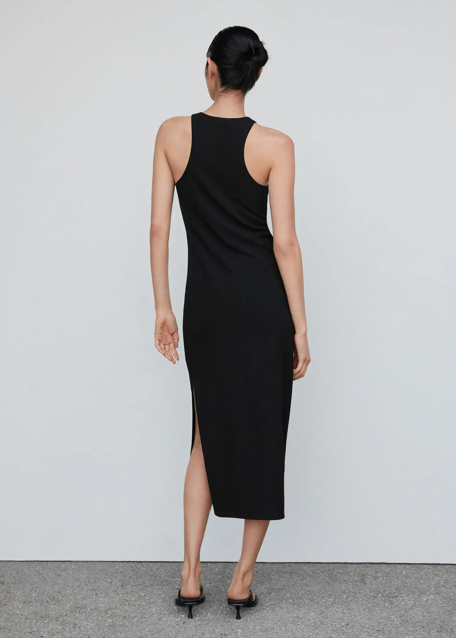 Mango Midi-dress with slit. a woman in a black dress is standing in front of a white wall. 