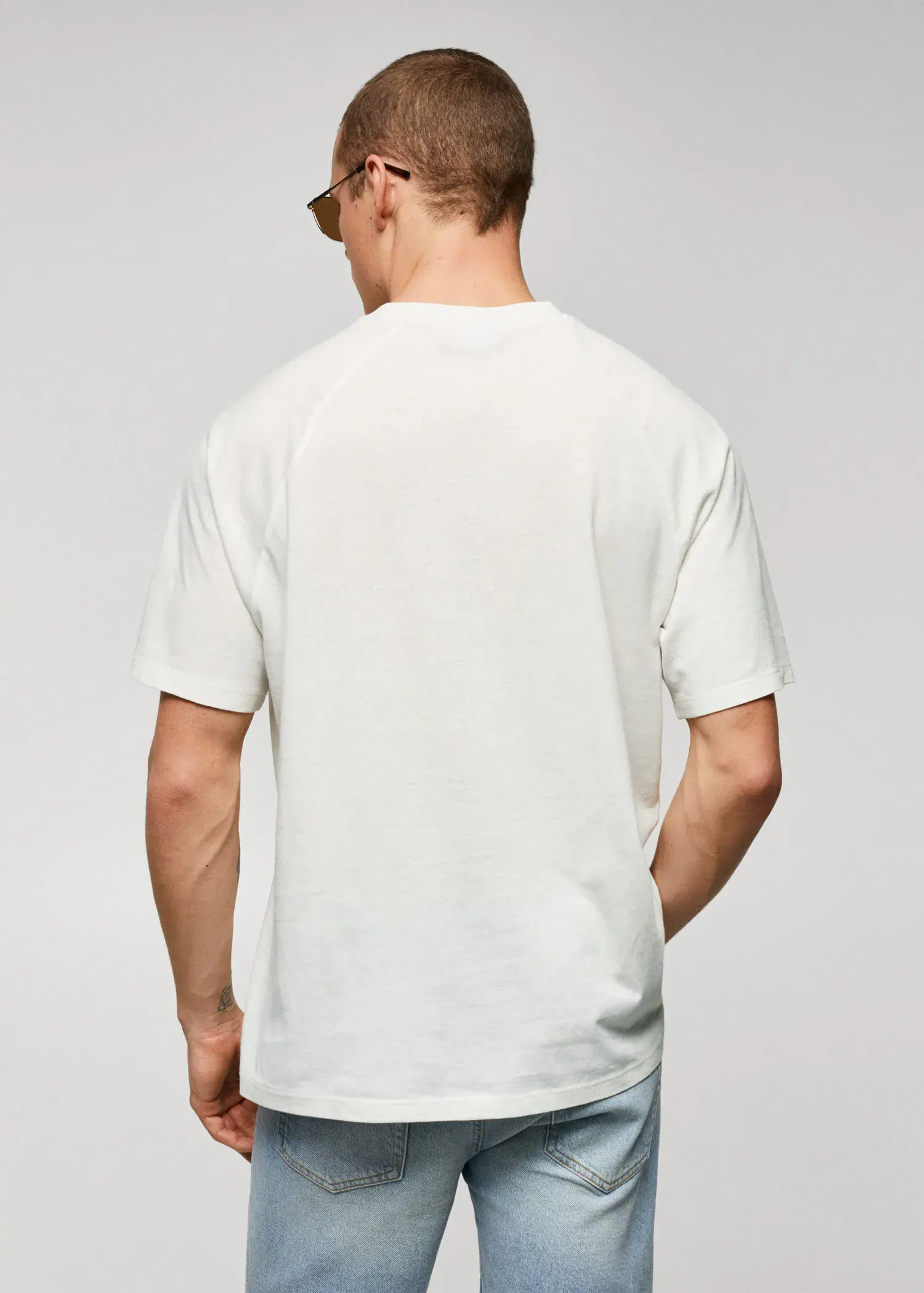 Mango Textured cotton-linen t-shirt. a man in a white shirt is standing with his hands in his pockets. 