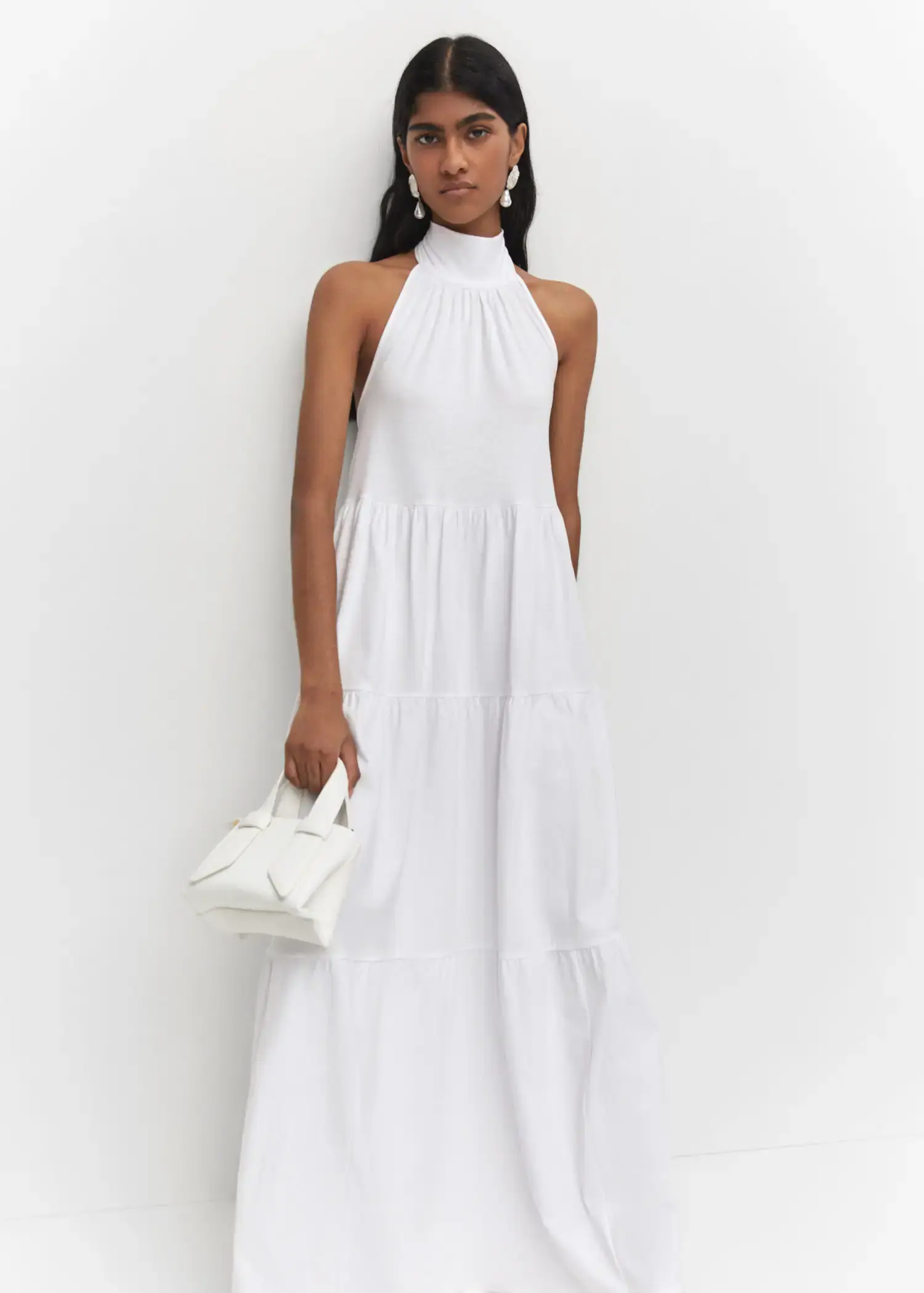 Mango Halter-neck open-back dress. a woman in a white dress holding a white purse. 