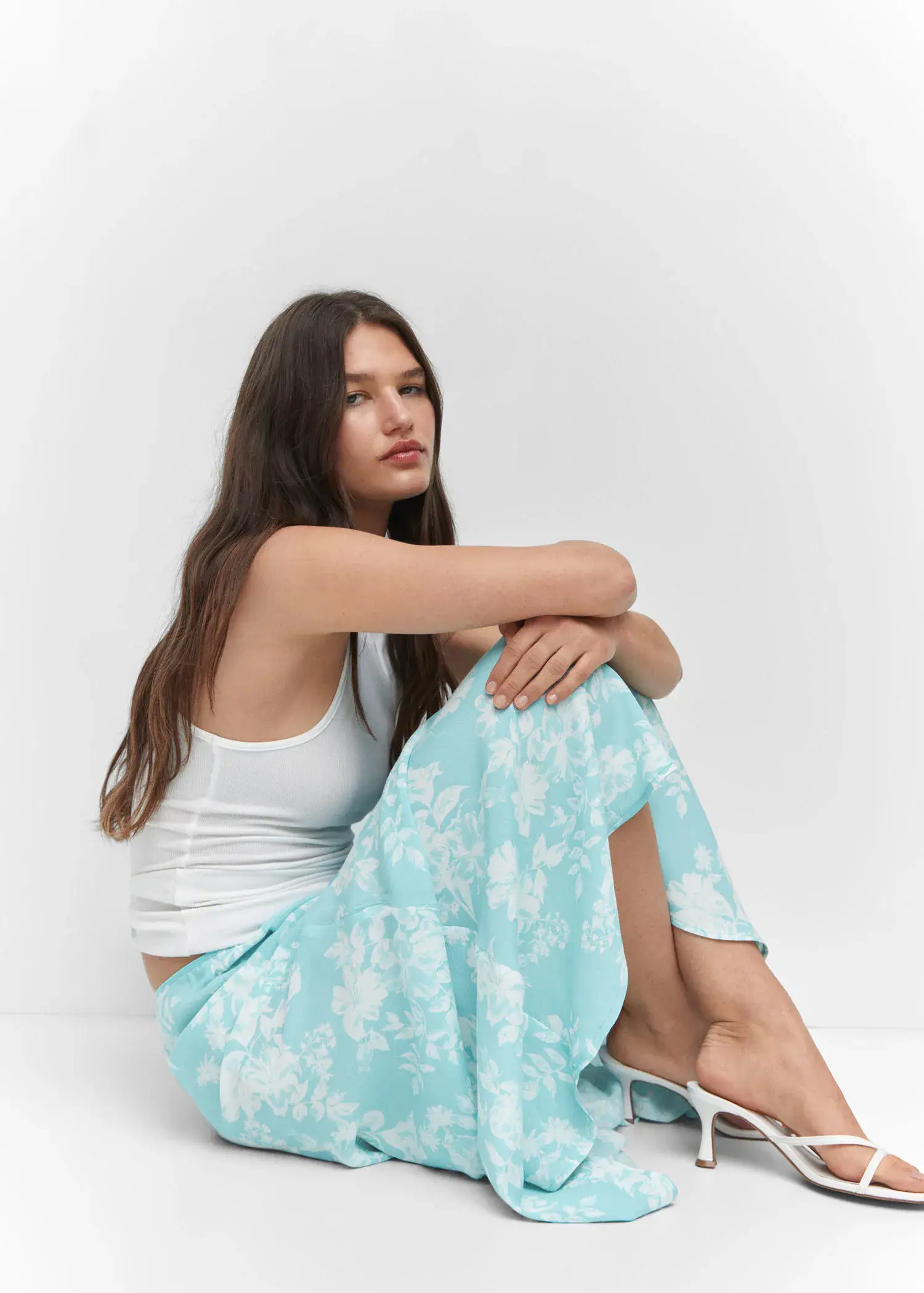 Mango Floral long skirt. a woman sitting on the ground wearing a white tank top. 