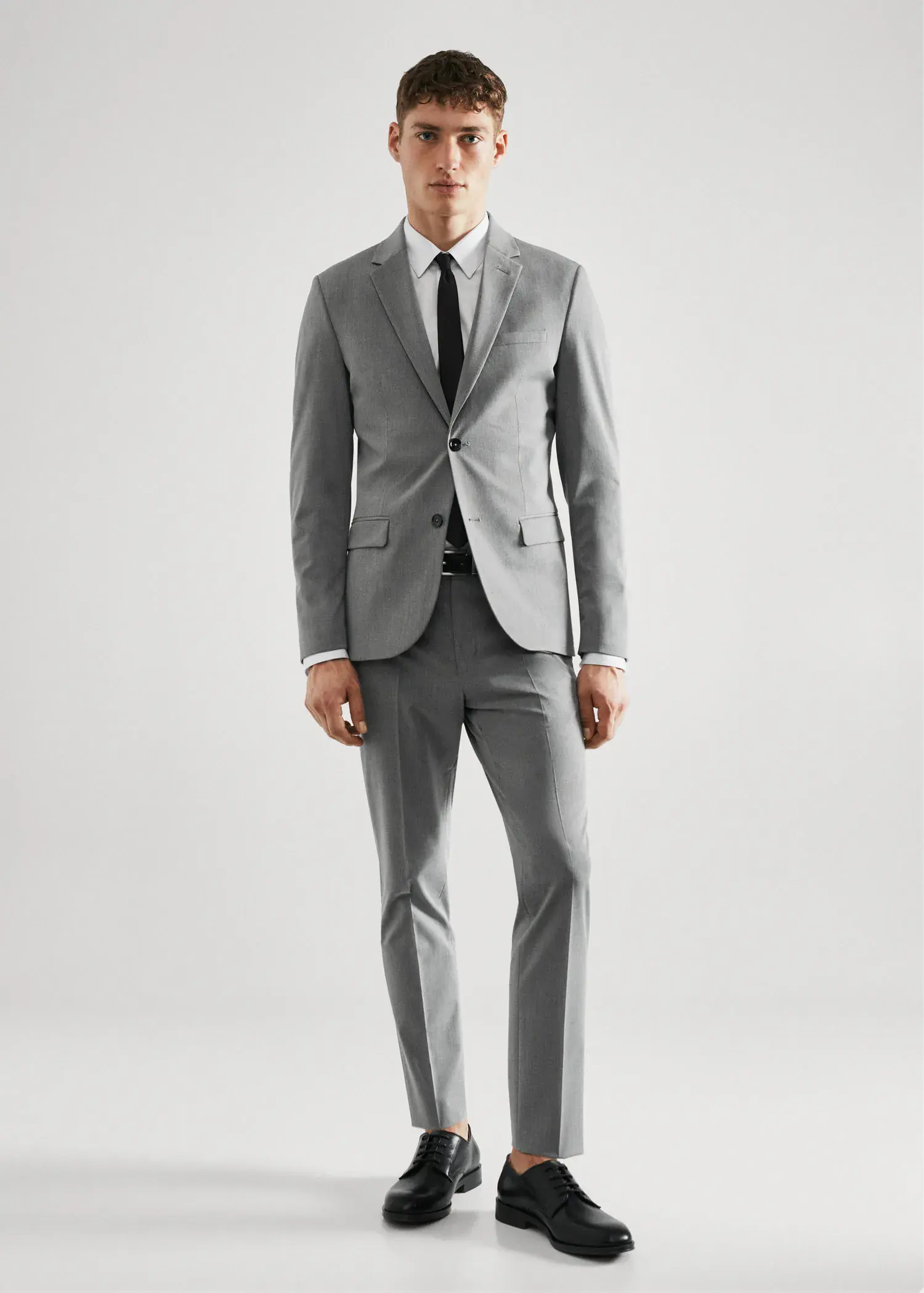 Mango Super slim-fit suit jacket in stretch fabric. a man wearing a suit and tie standing in a room. 