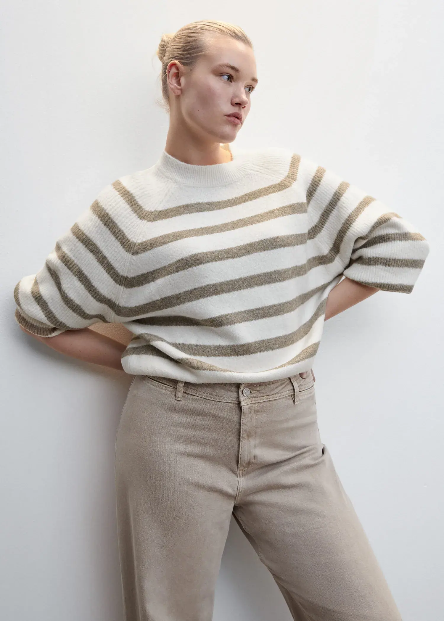 Mango Stripe-print sweater with Perkins neck. a woman leaning against a wall with her hands behind her head. 