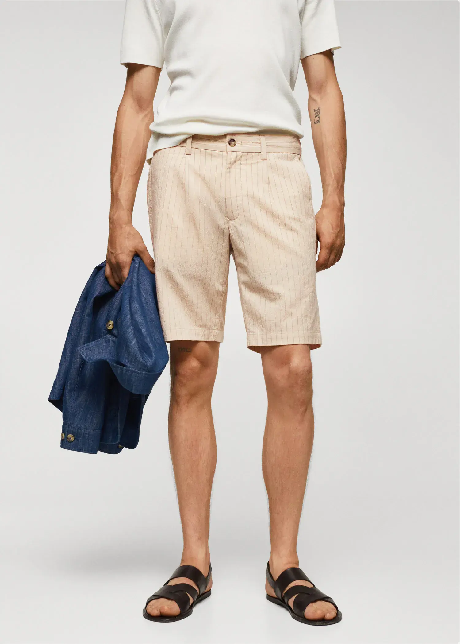 Mango Pinstripe seersucker Bermuda shorts. a man holding a jacket and wearing shorts. 
