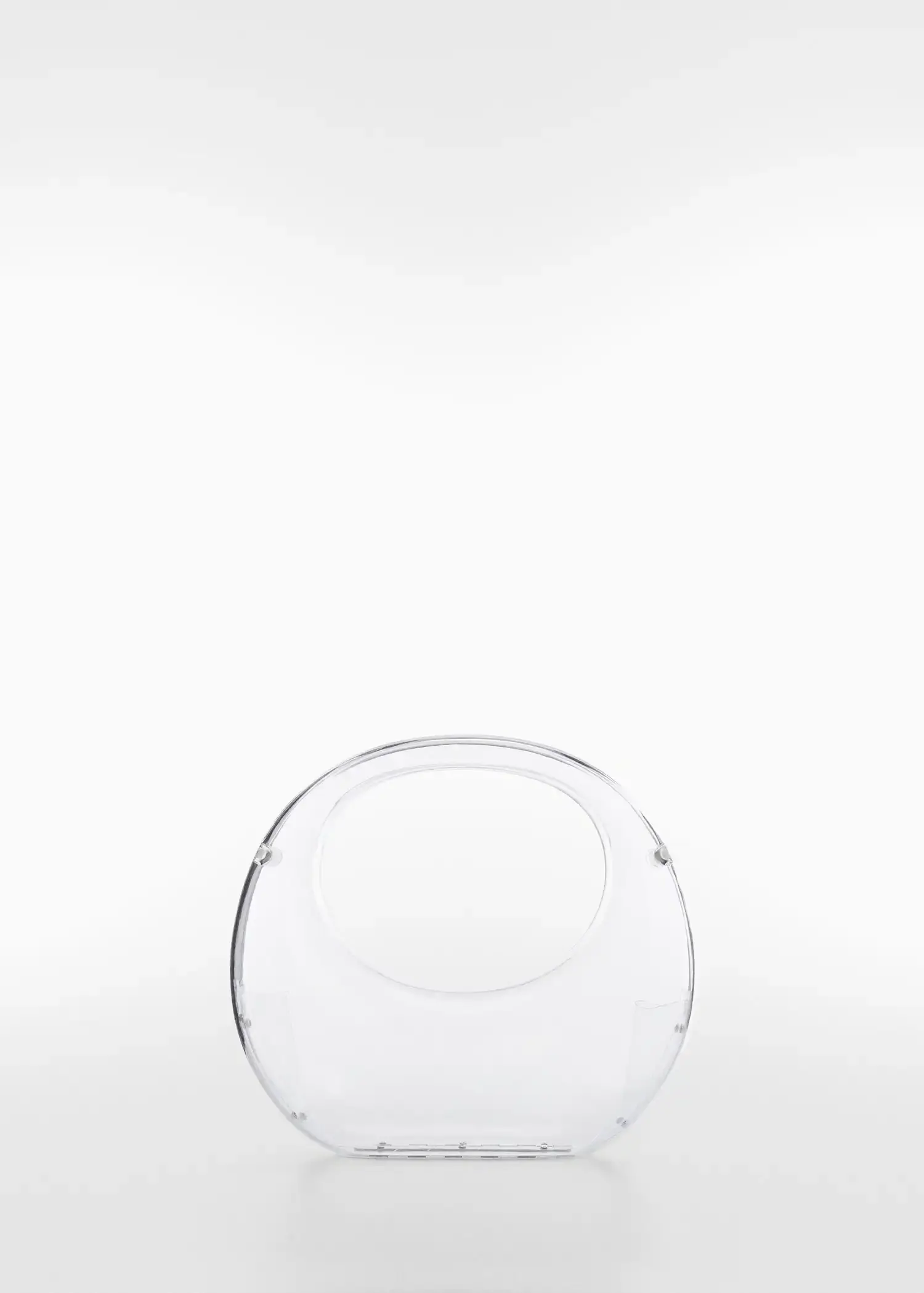 Mango Transparent rigid bag. an empty glass purse sitting on top of a white table. 