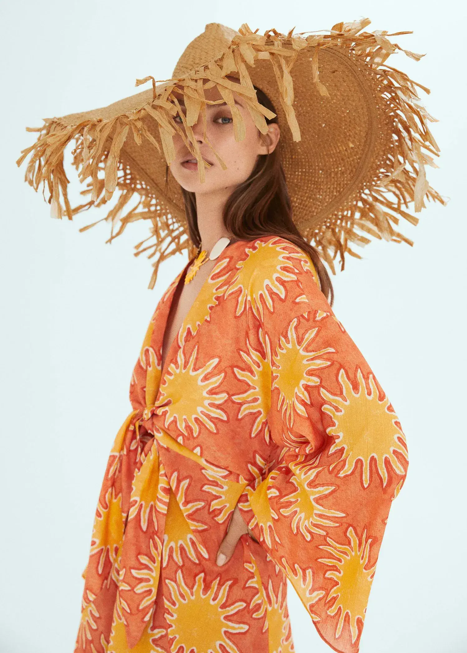 Mango Natural fiber maxi hat. a woman wearing a sun hat standing in front of a blue background. 