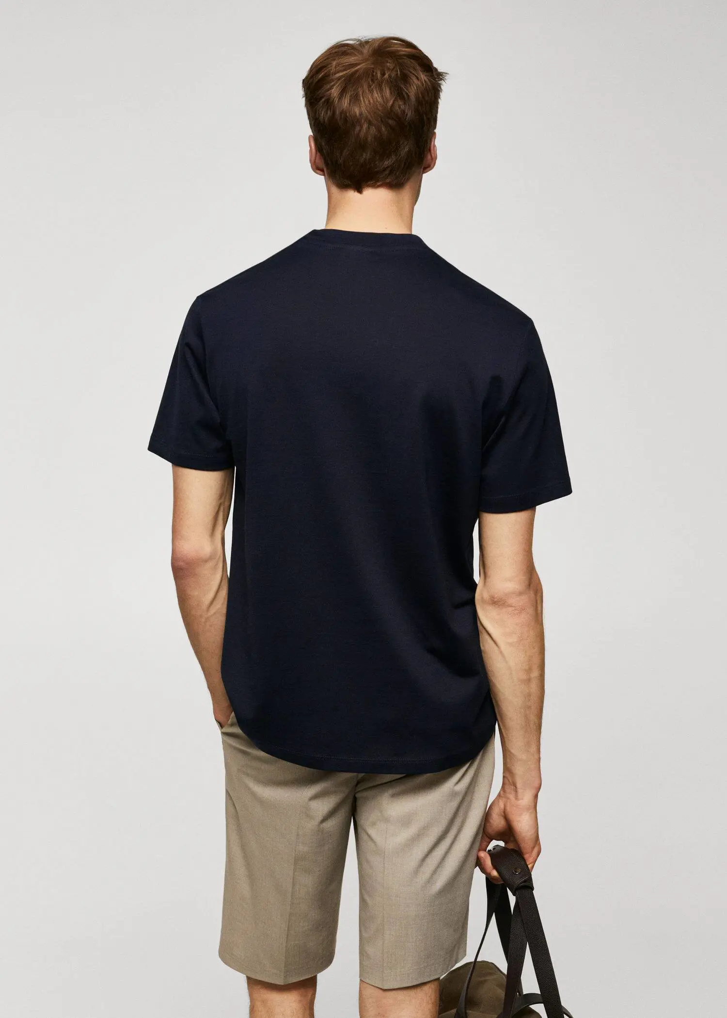 Mango Mercerized regular-fit t-shirt. a man in a black shirt is holding a phone 