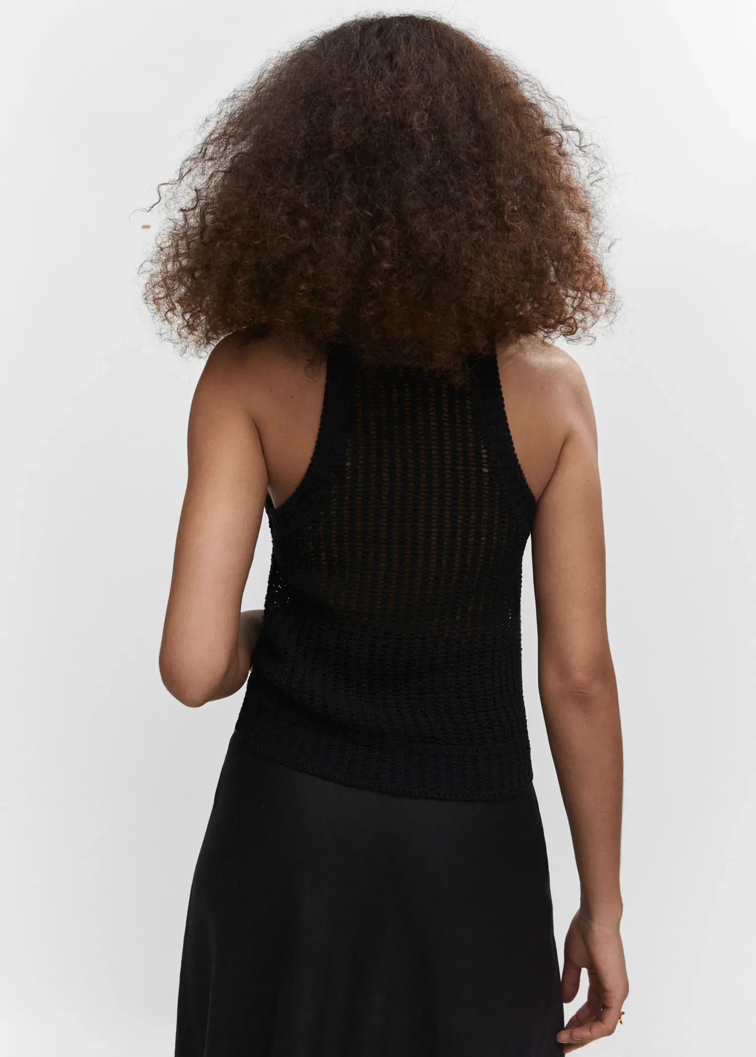 Mango Halter-neck knitted top. a woman with curly hair wearing a black top. 