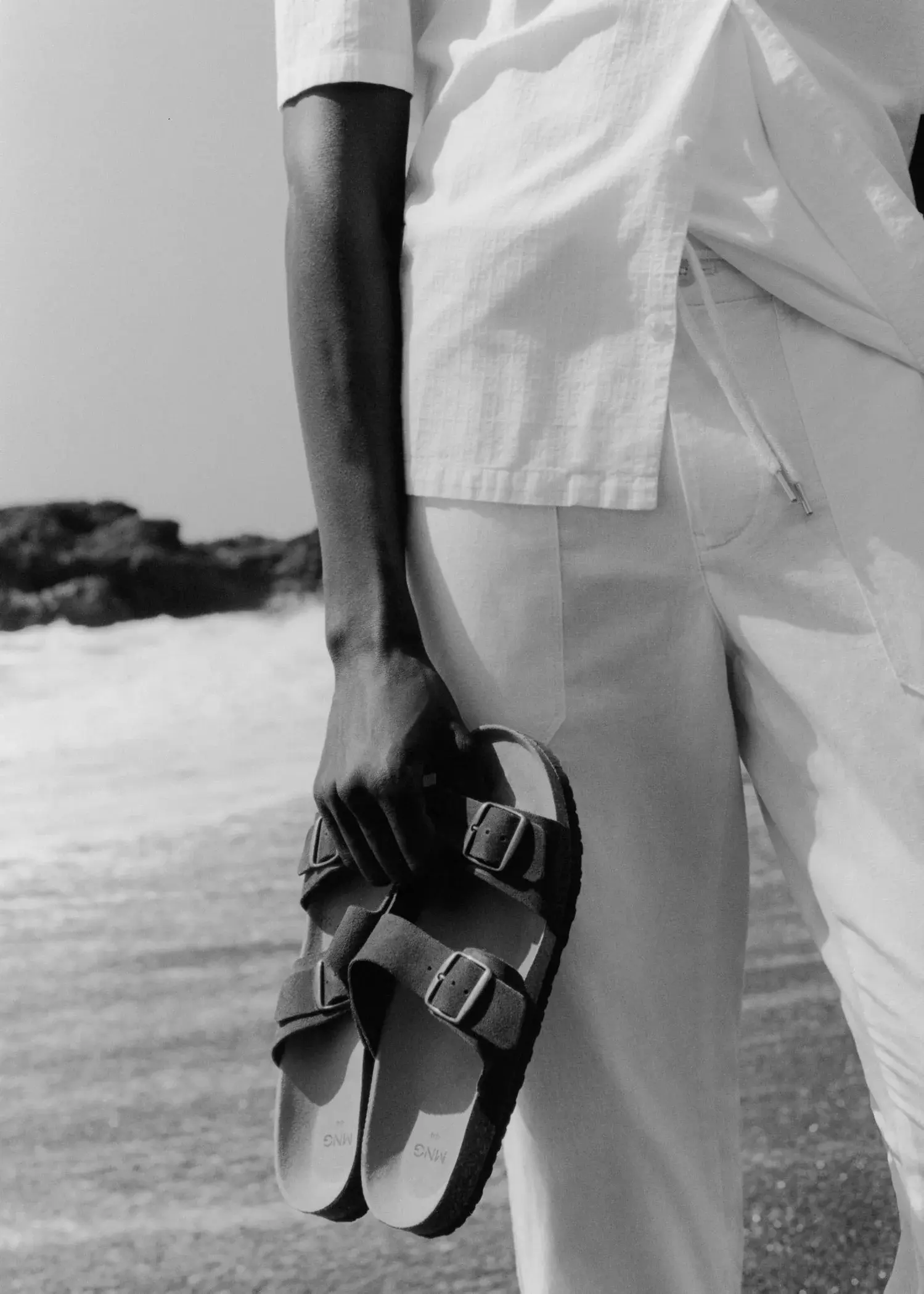 Mango Split leather sandals with buckle. a person holding a pair of sandals on the beach. 