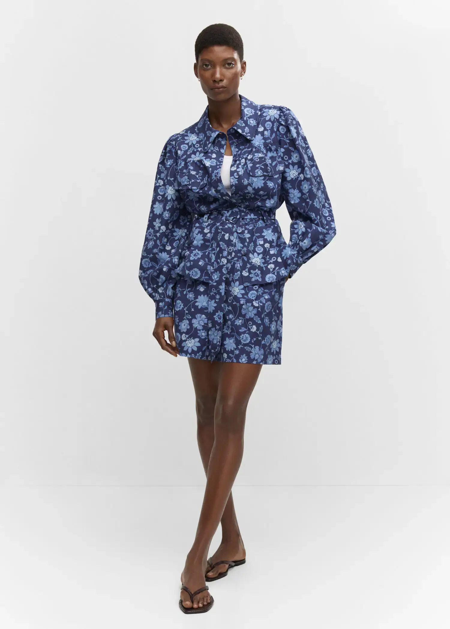 Mango Floral overshirt with belt. a woman in a blue floral dress standing in a room. 