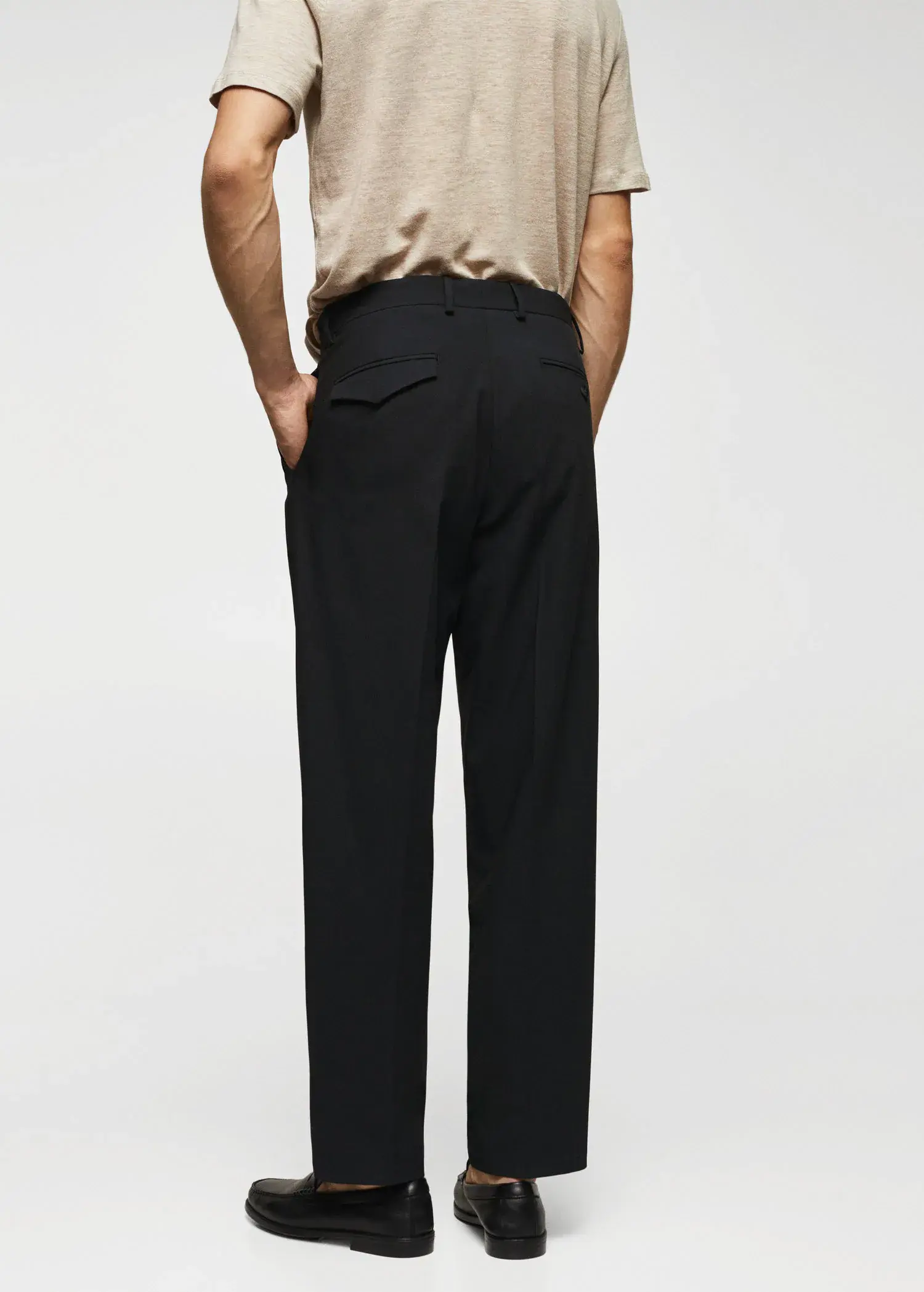 Mango Regular fit pleated cotton trousers. a man standing with his hands in his pockets. 