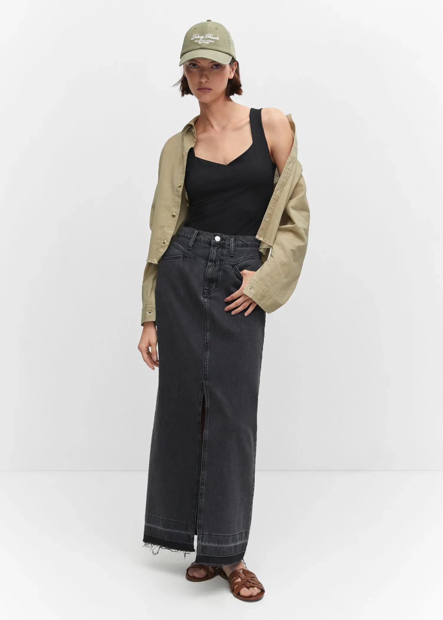 Mango Open elastic top. a woman in a black skirt and a tan jacket. 