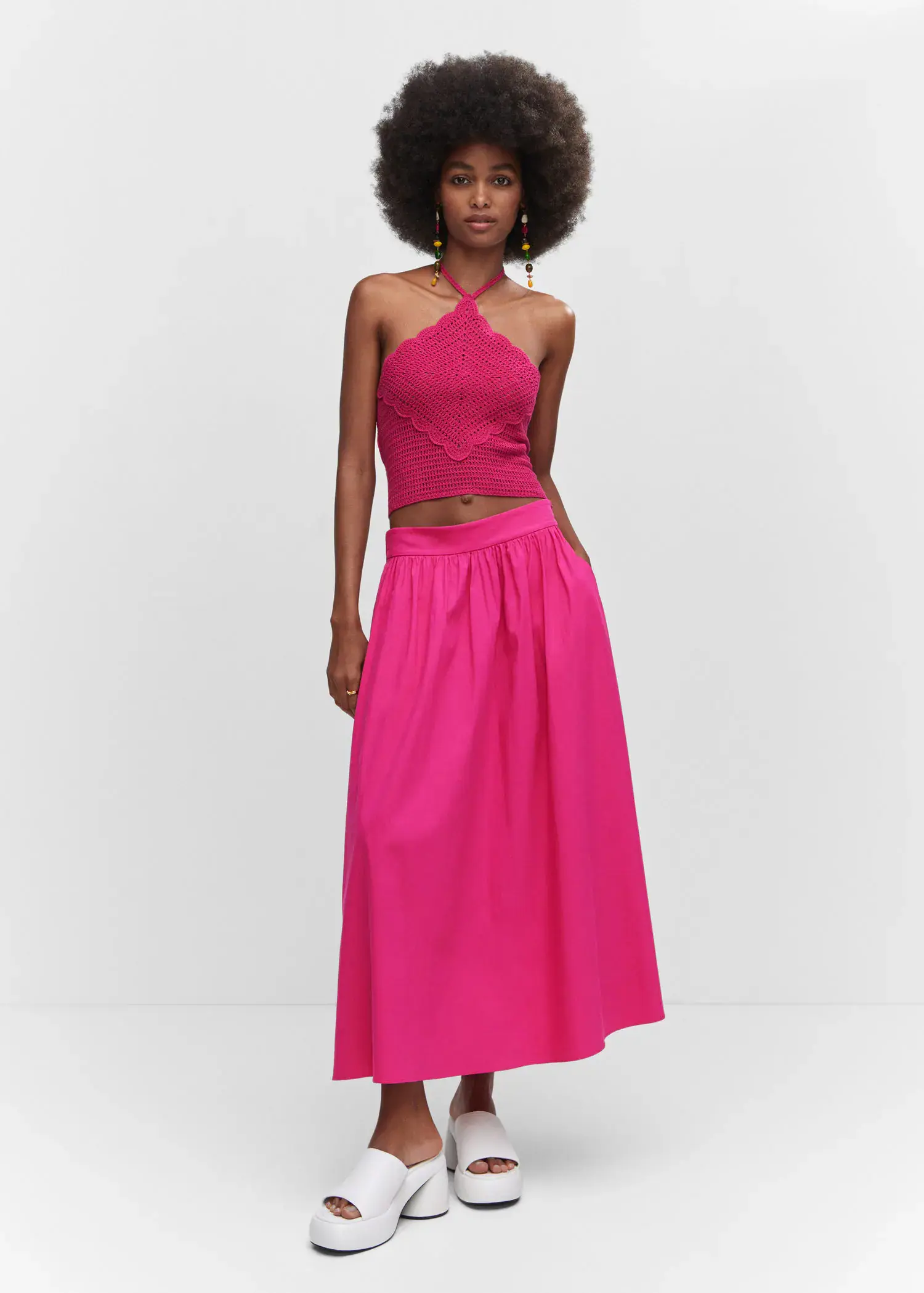 Mango Pleat detail long skirt. a woman wearing a pink dress standing in front of a wall. 