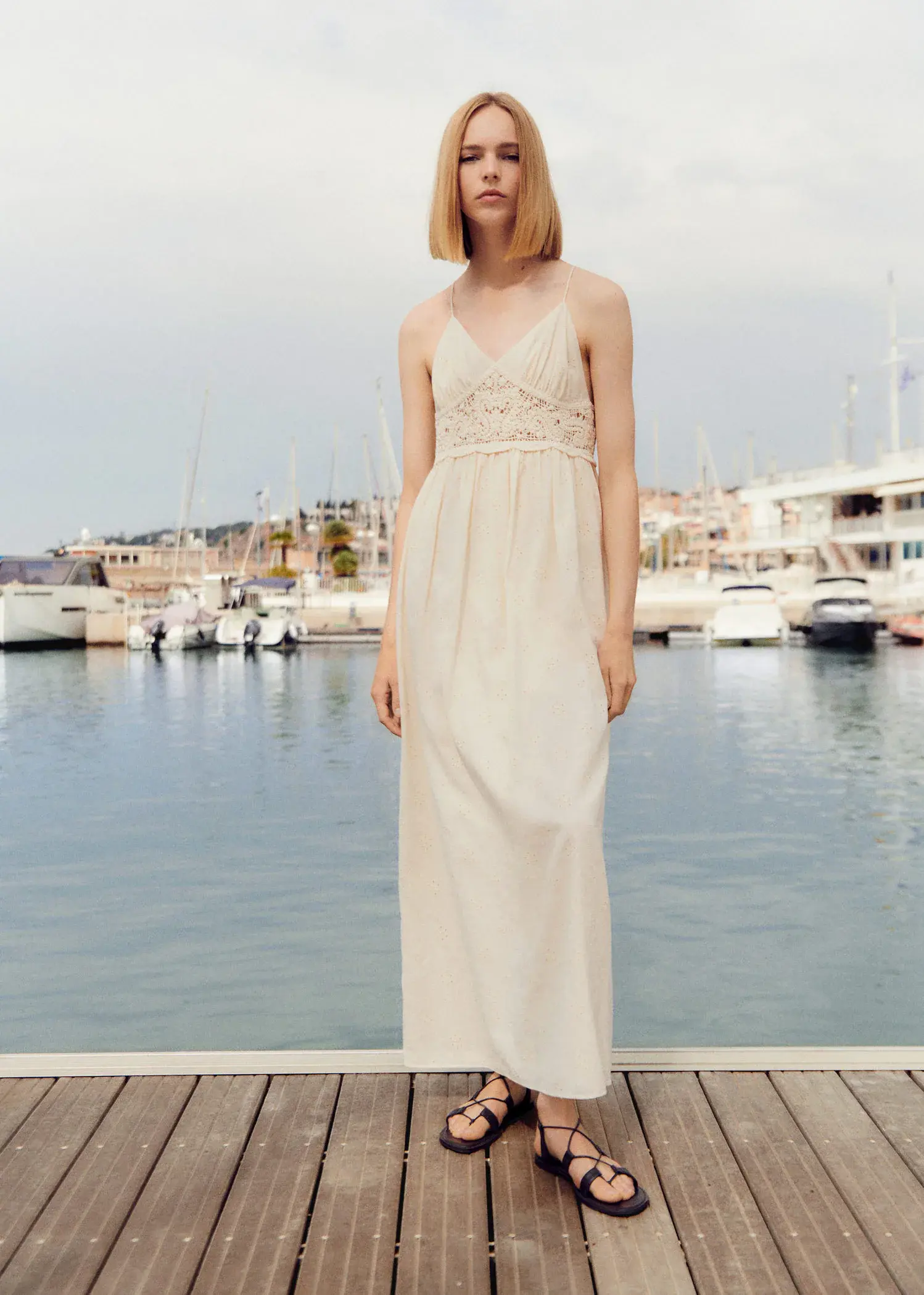 Mango Crochet panel dress. a woman standing on a dock in front of boats. 