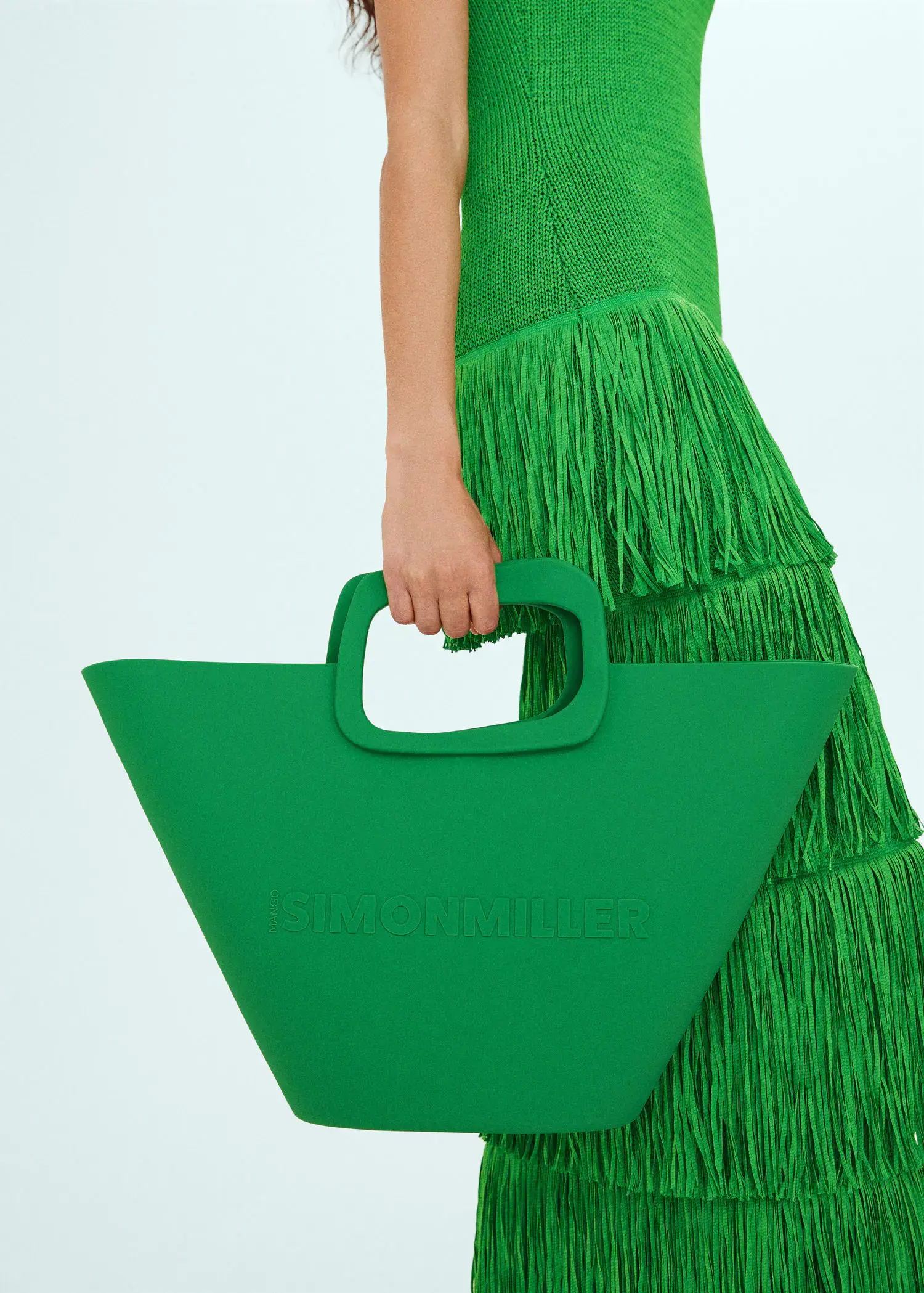 Mango Bag with geometric logo design. a person in a green dress holding a bag. 